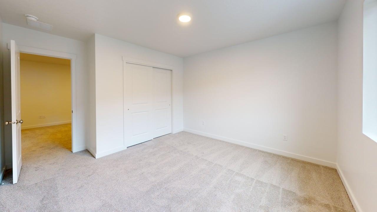 Carpeted interior space featuring white walls, a single window, an open doorway, and a closet with sliding panel doors