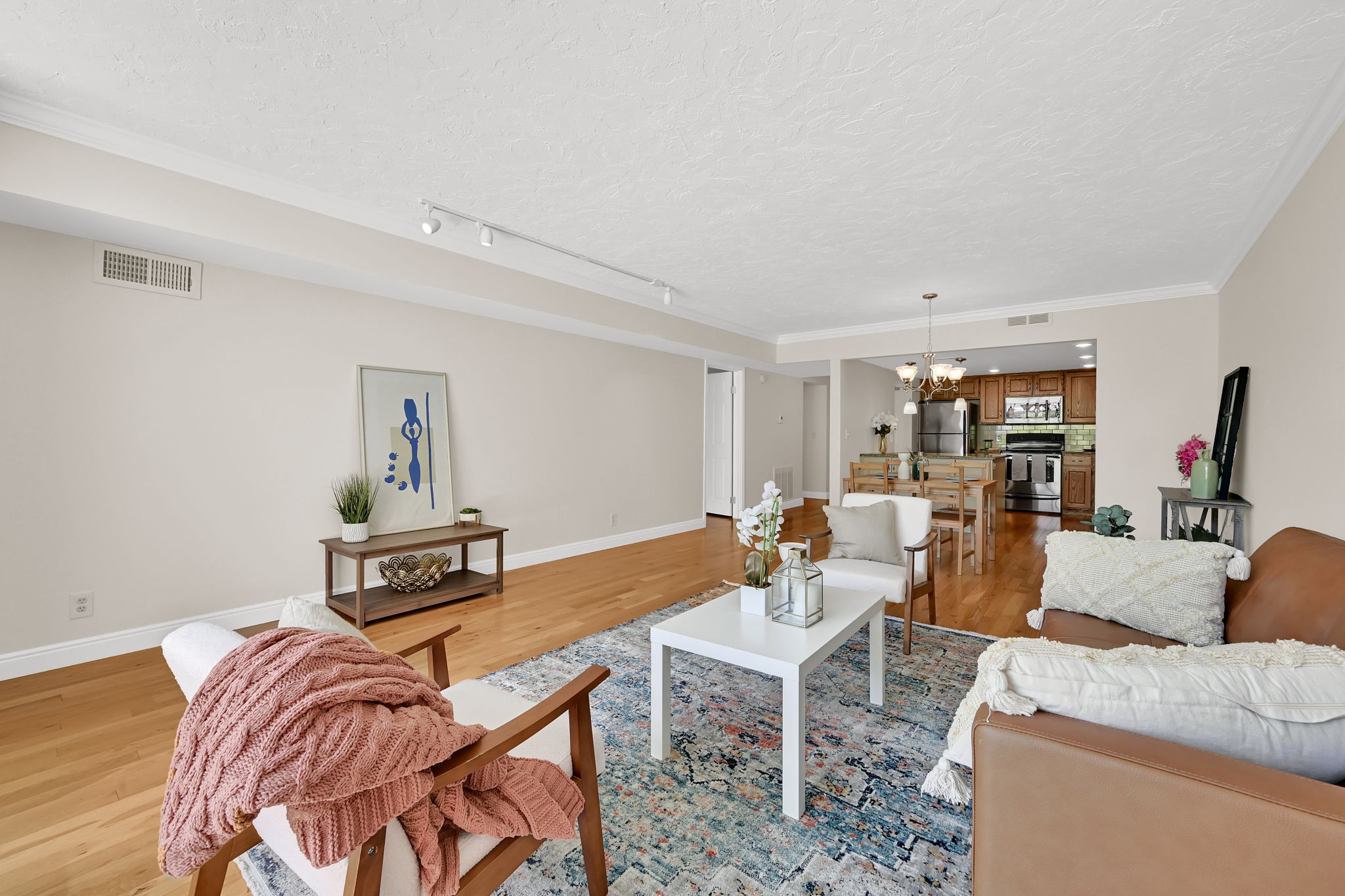 Open-concept living area featuring wood-finish flooring, recessed lighting, and crown molding