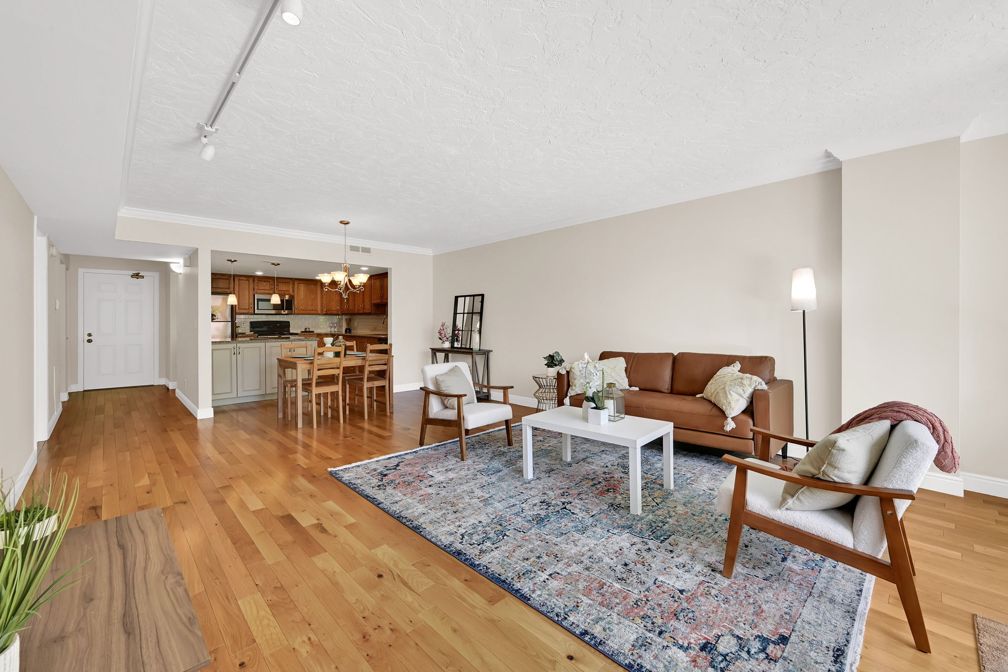 Open-concept living area featuring wood-finish flooring, neutral wall tones, and recessed track lighting