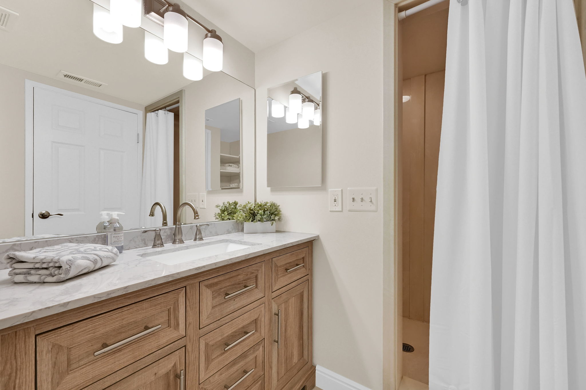 Bathroom featuring a wood-finish vanity with a light-toned countertop, an undermount sink, and brushed nickel fixtures