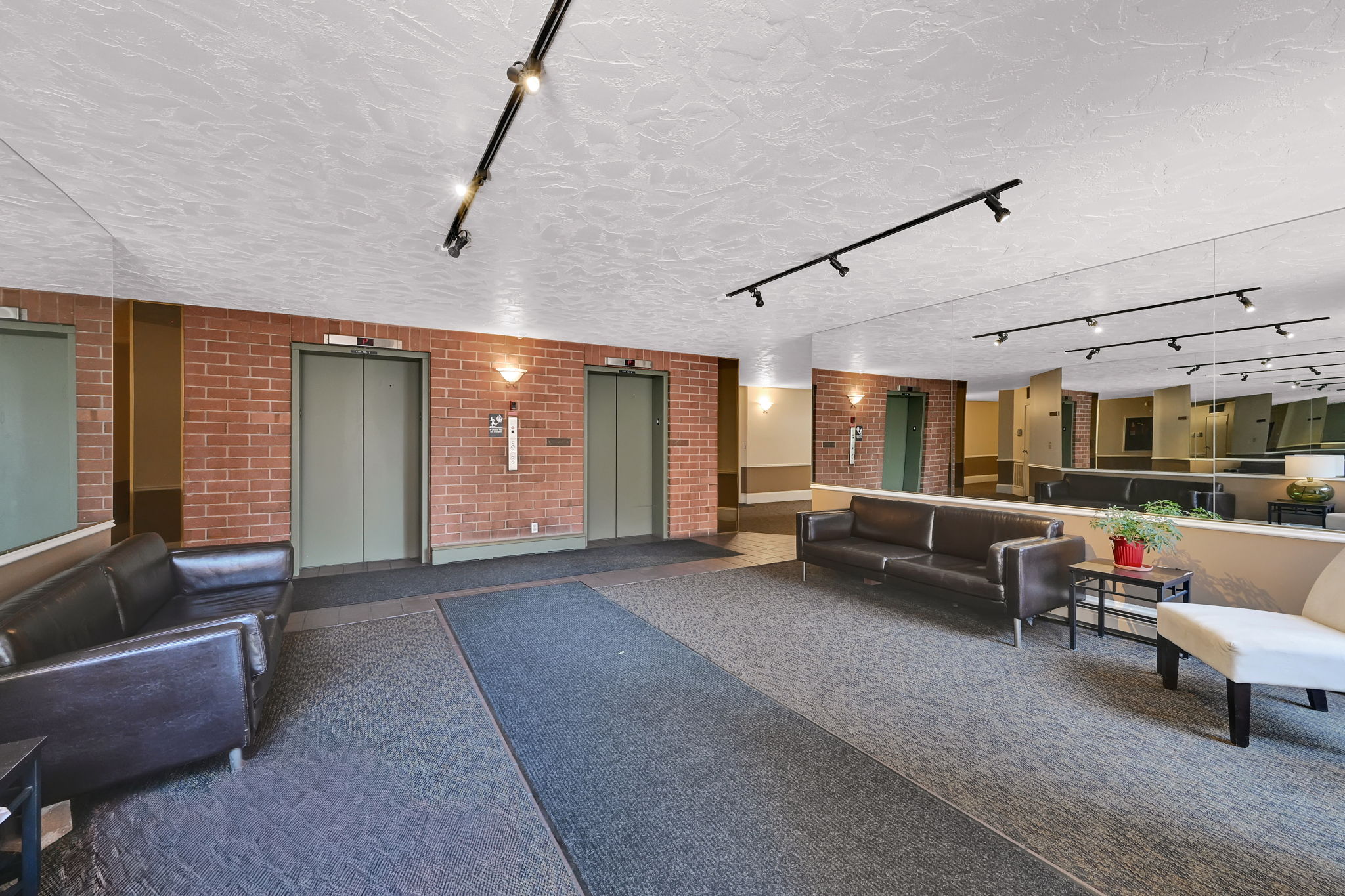 Lobby area featuring two elevators, brick accent walls, and recessed lighting