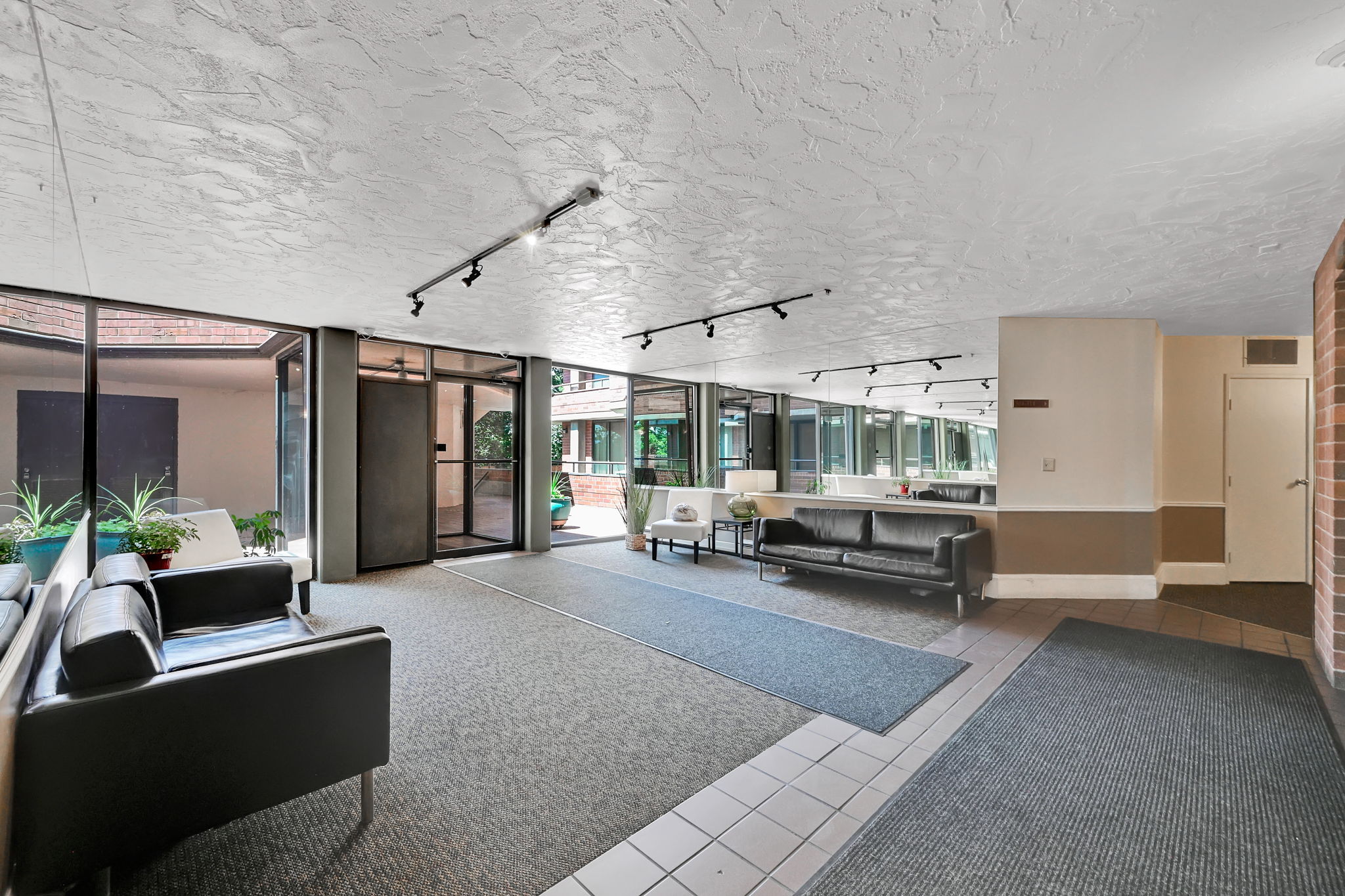 Lobby entrance featuring full-height windows, track lighting, and a textured ceiling