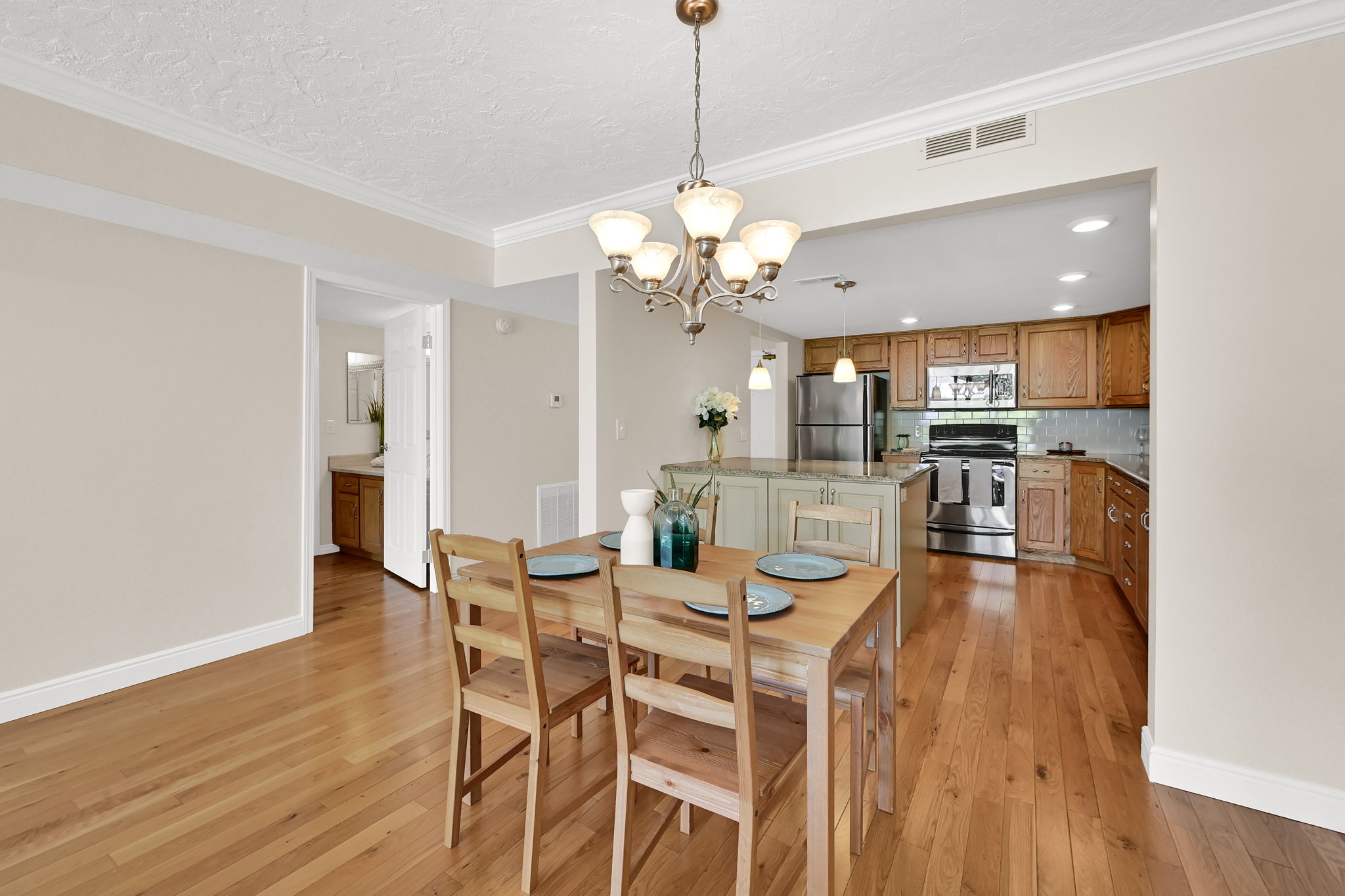 Open-concept dining area with wood-finish flooring, crown molding, and a traditional chandelier