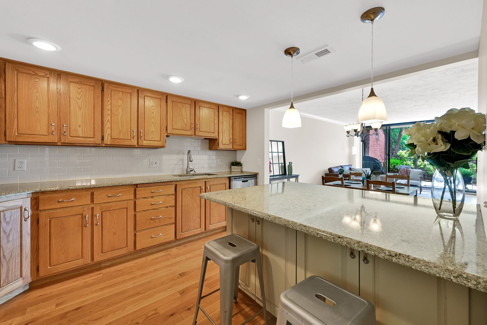 Kitchen featuring wood cabinetry, light-toned granite countertops, and a subway tile backsplash