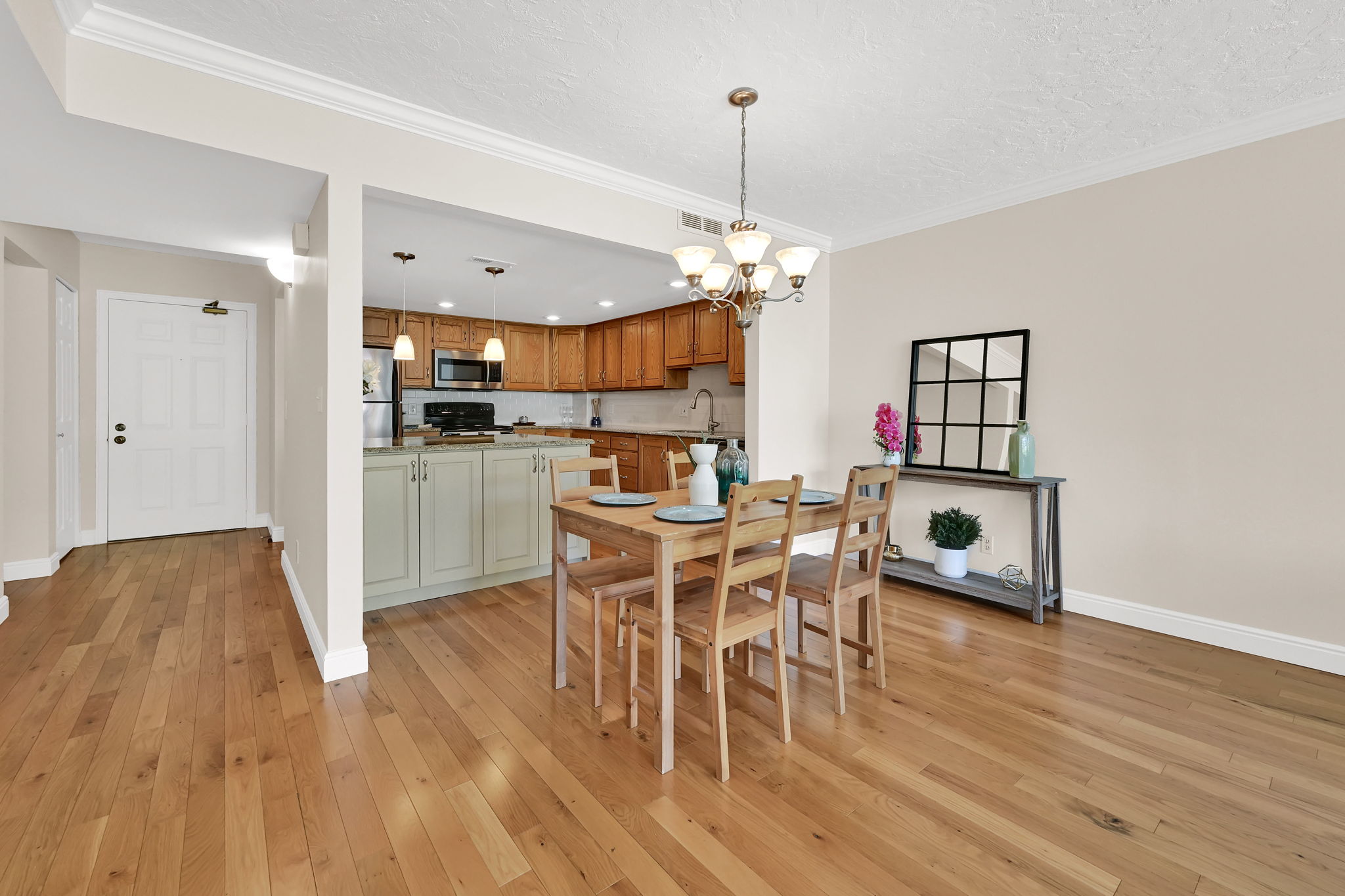 Open-concept dining and kitchen area featuring wood-finish flooring throughout