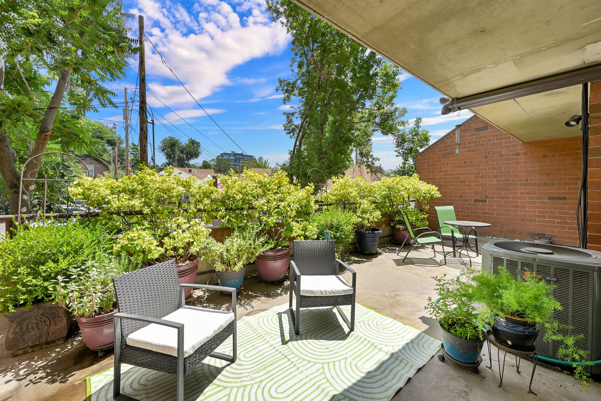 Paved patio area featuring lush potted plants and a brick exterior wall