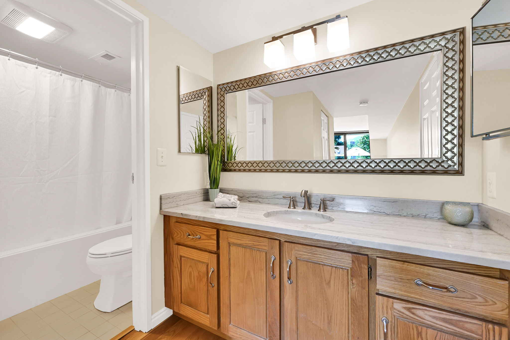 Bathroom featuring a wood vanity with a white countertop and undermount sink, accented by a decorative framed mirror