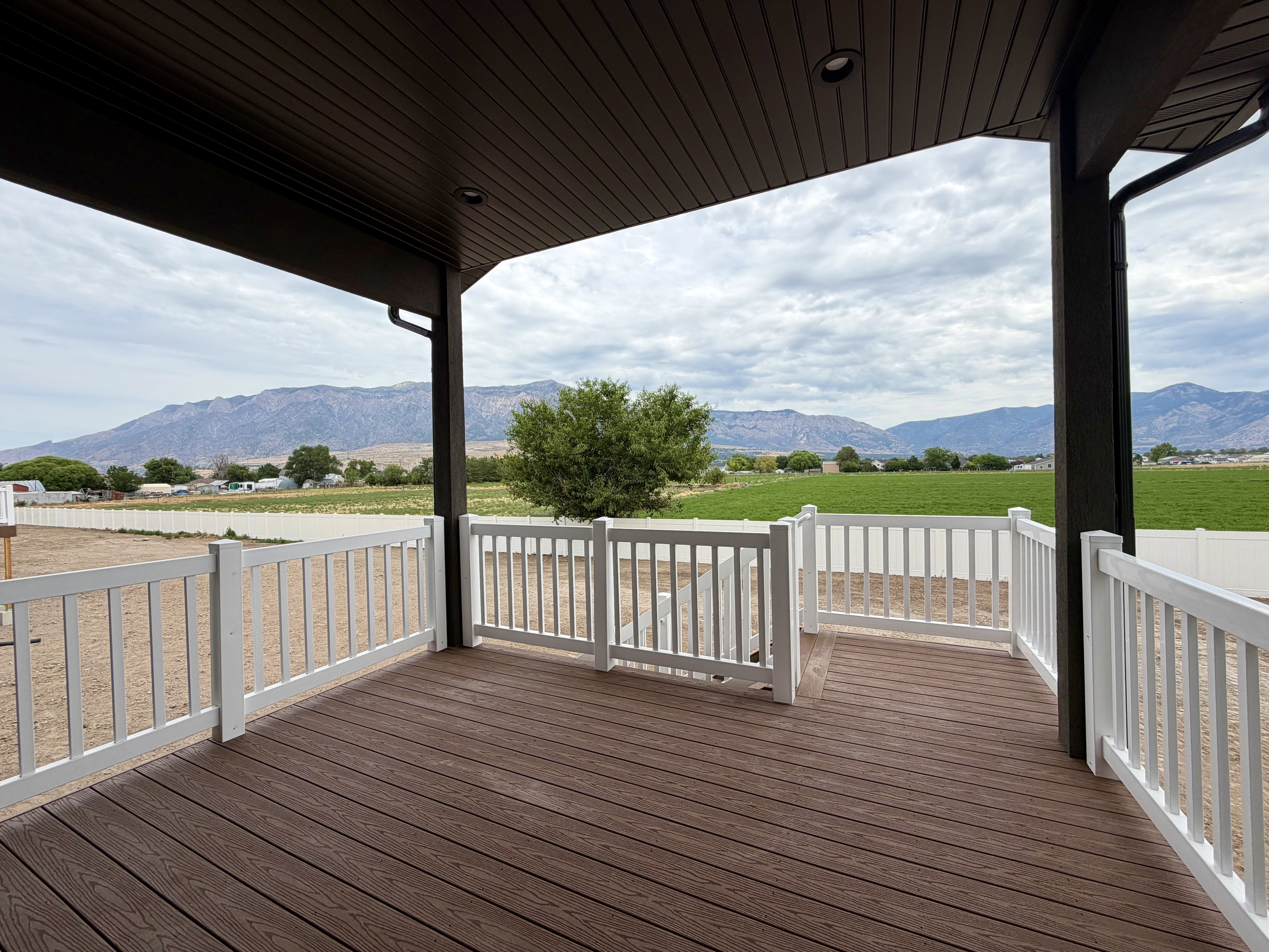 Covered deck featuring wood-finish composite decking and white railings