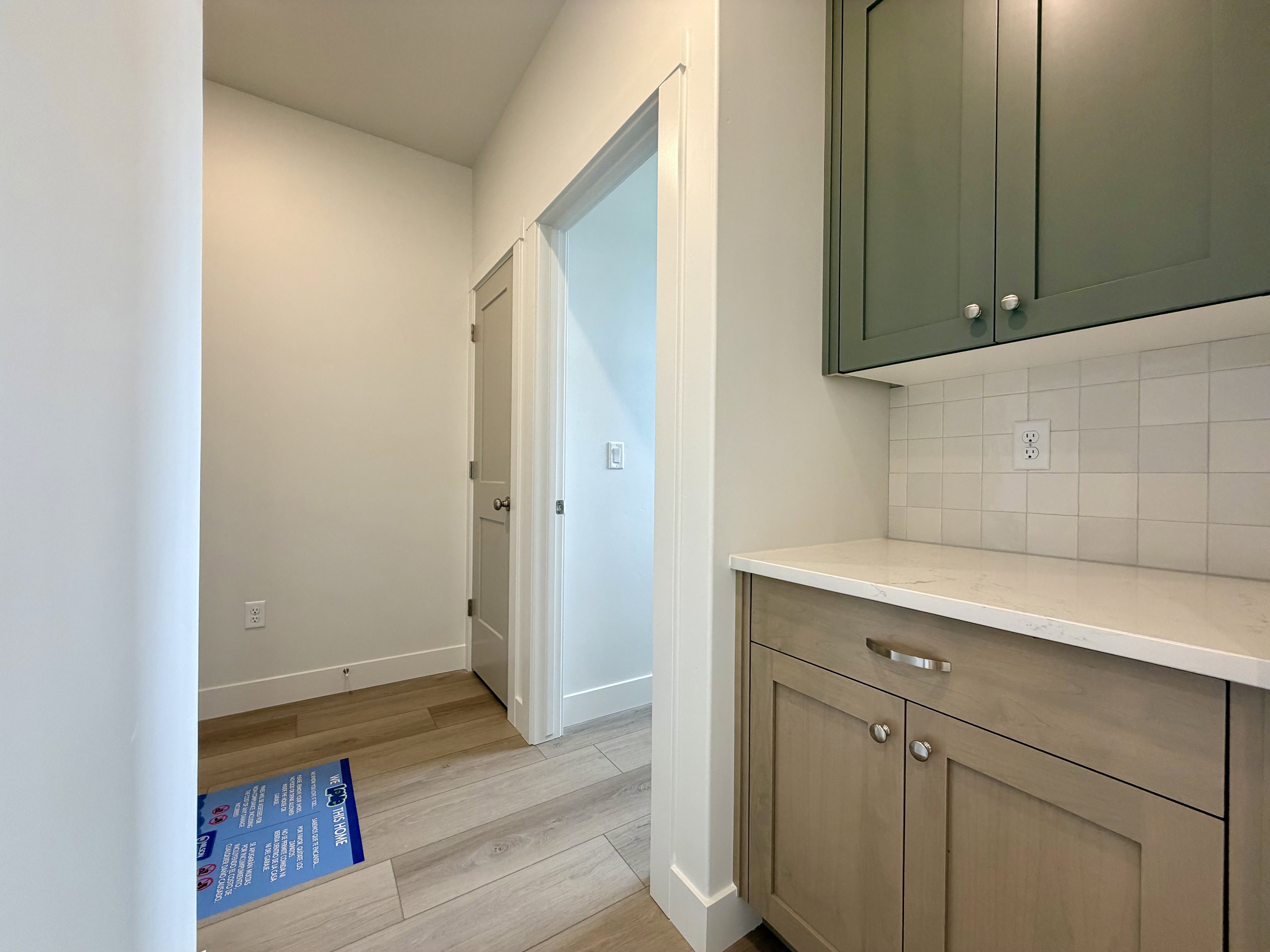 Custom cabinetry featuring two-tone finishes, solid surface countertop, and square tile backsplash
