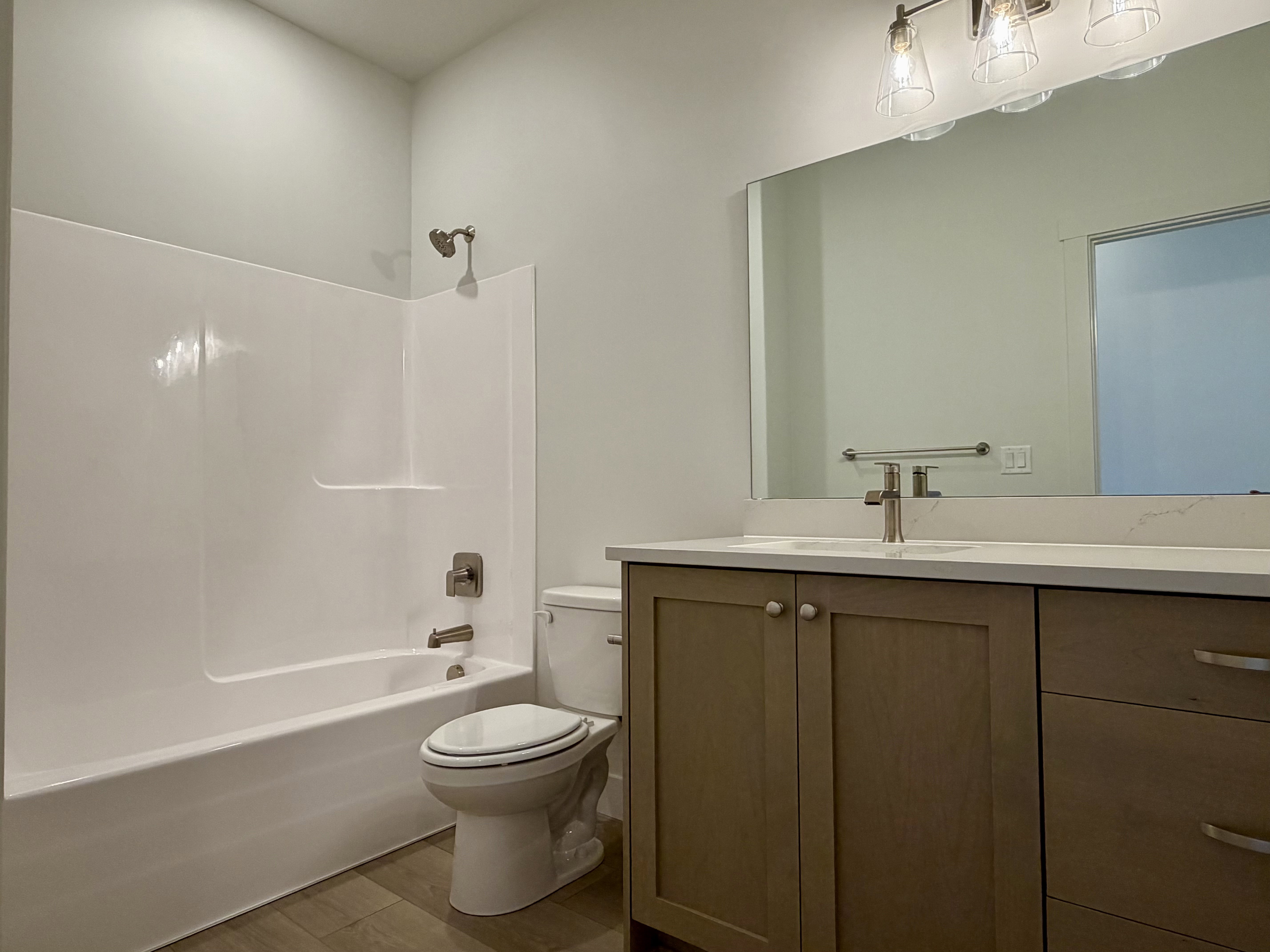 Modern bathroom featuring a single vanity with shaker-style cabinetry, a light-toned countertop, a rectangular mirror, and an overhead light fixture