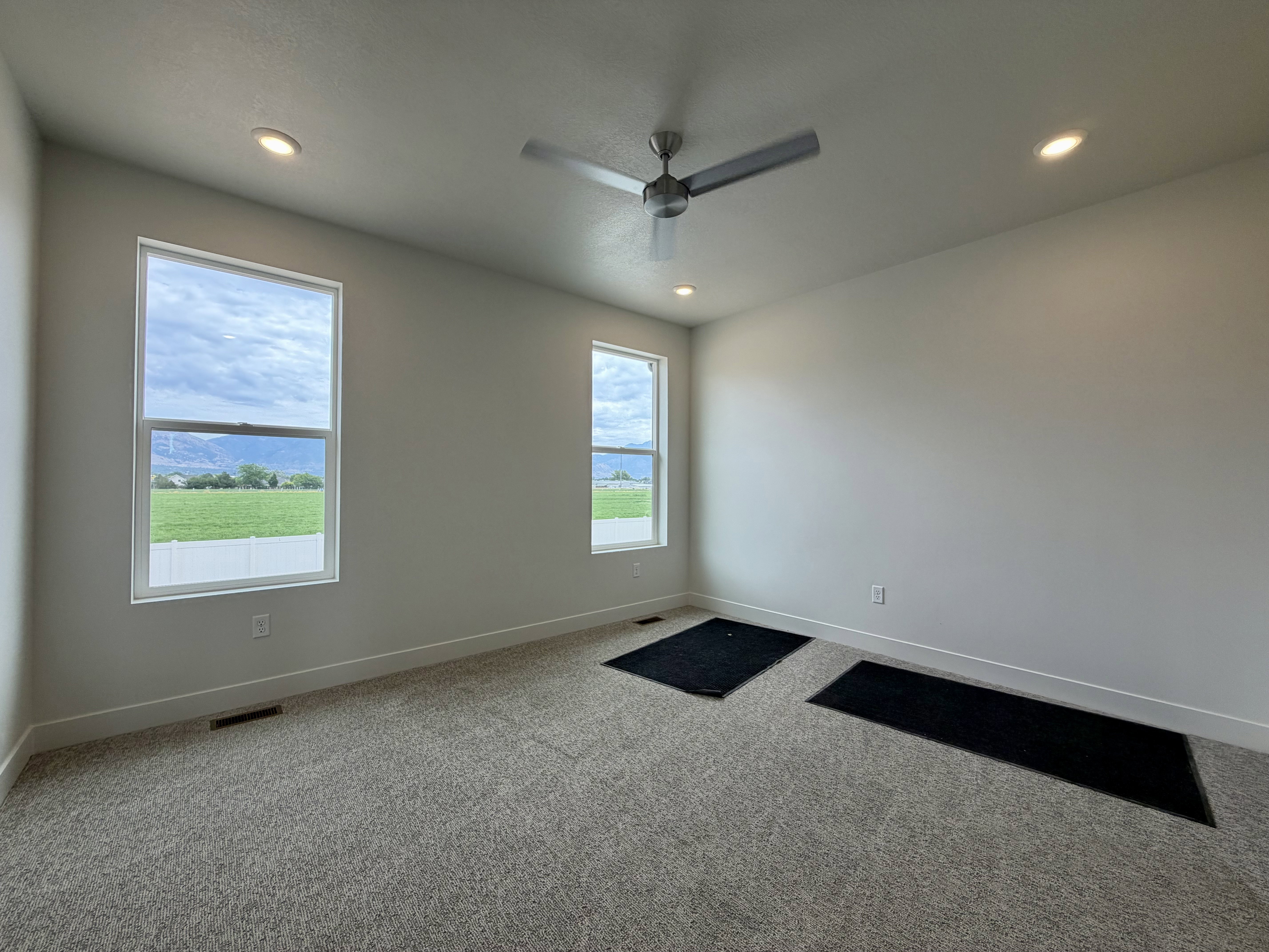 Bright interior room with two large windows, a ceiling fan, and recessed lighting