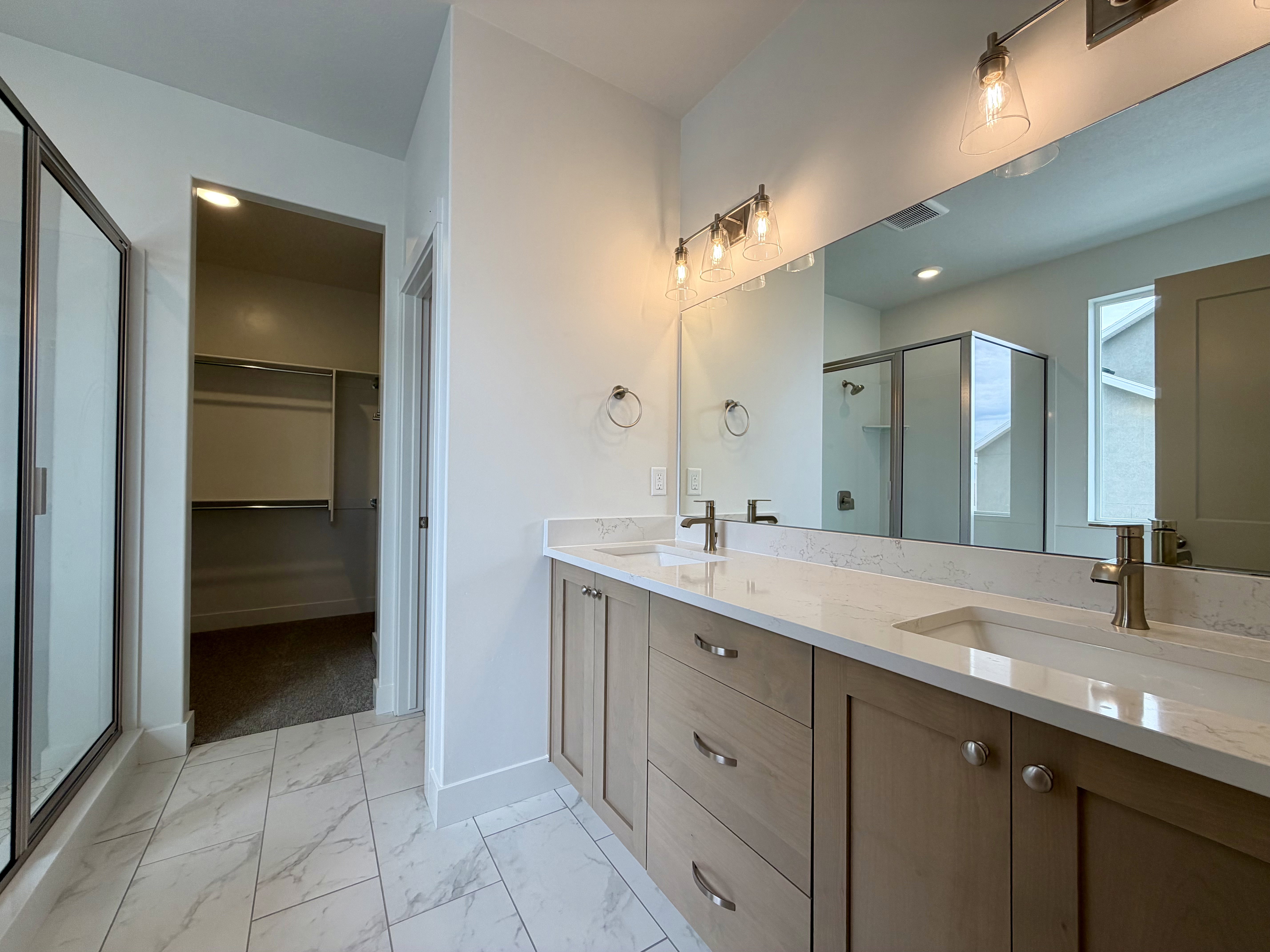 Double vanity with light wood-finish cabinetry and white countertops