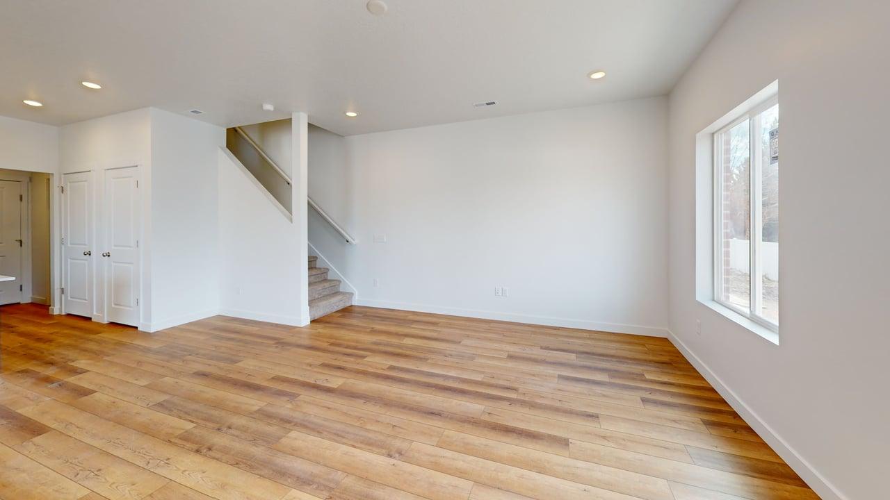 Open concept living space featuring wood-finish flooring, recessed lighting, a white framed window, and a carpeted staircase