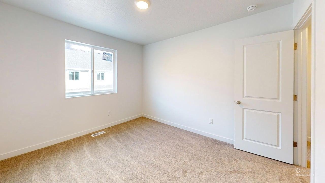 Neutral-toned carpeting paired with white walls, a single window, and a paneled door