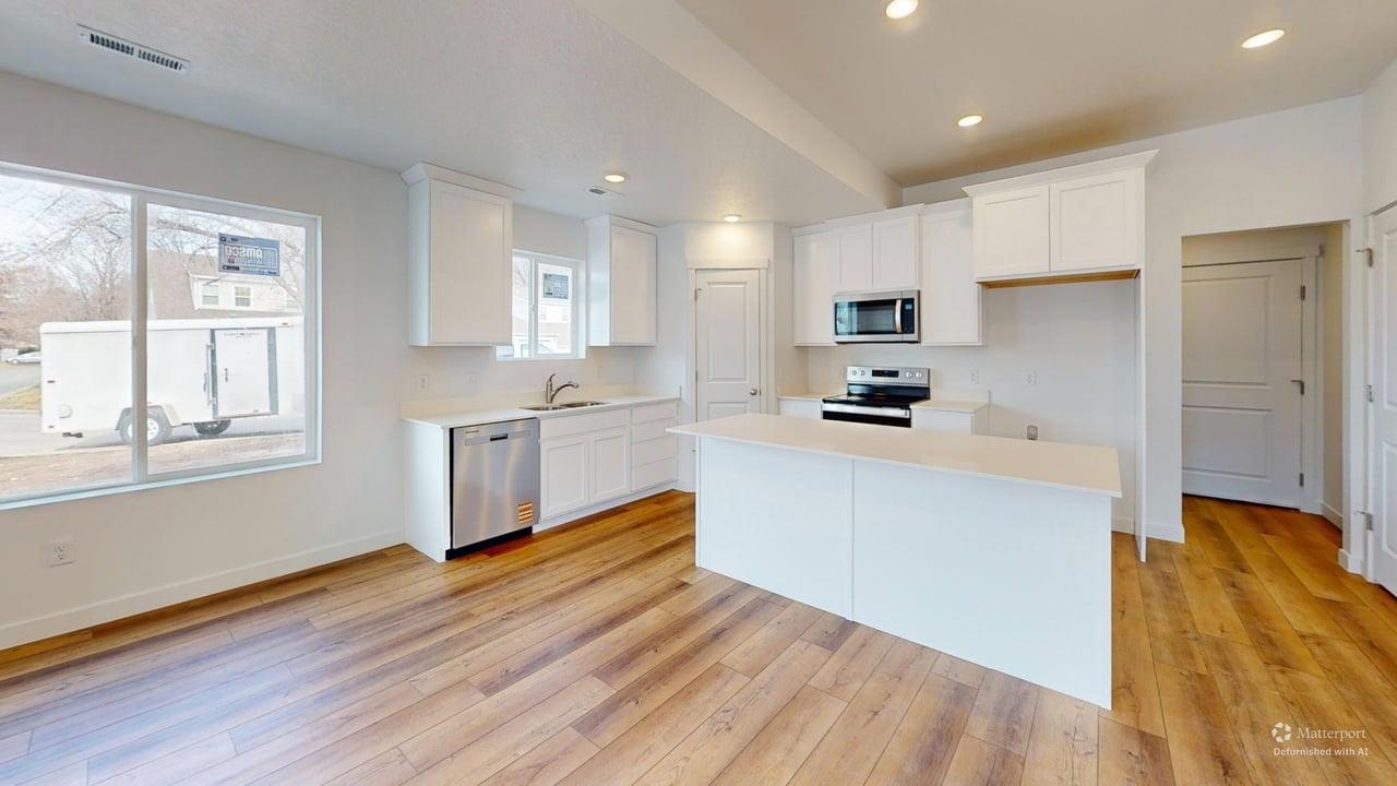 Modern kitchen featuring a central island, white cabinetry, stainless steel appliances, and wood-finish flooring