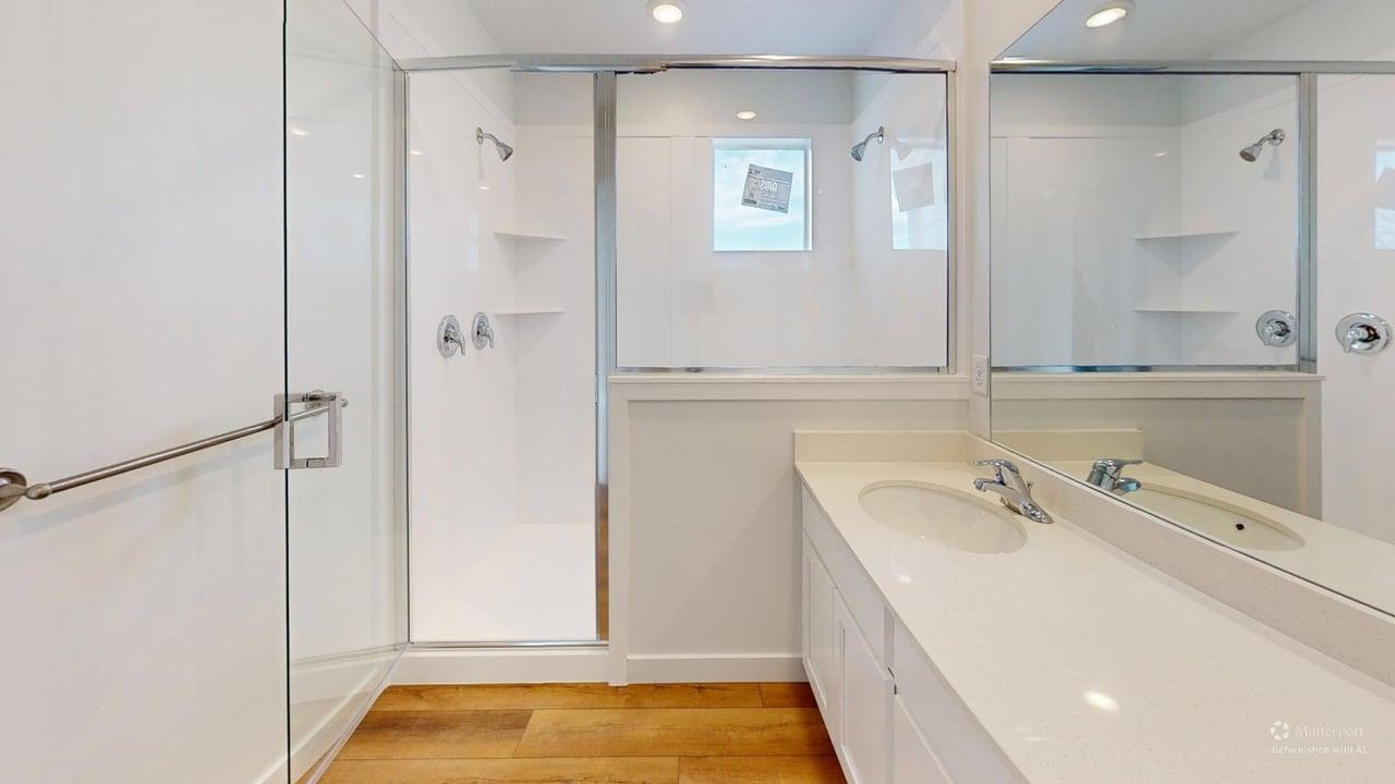Bathroom featuring a frameless glass-enclosed shower with chrome fixtures and integrated shelving