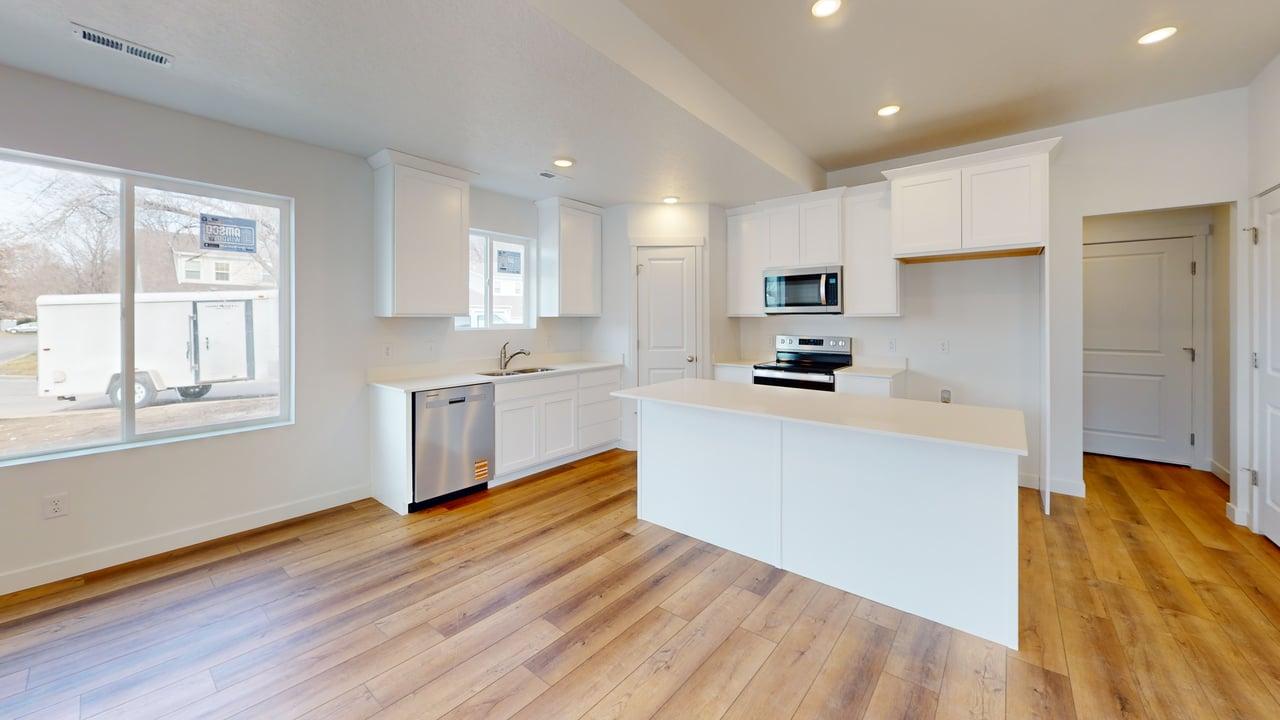 Modern kitchen featuring wood-finish flooring, white cabinetry, a central island, stainless steel dishwasher, and an over-range microwave