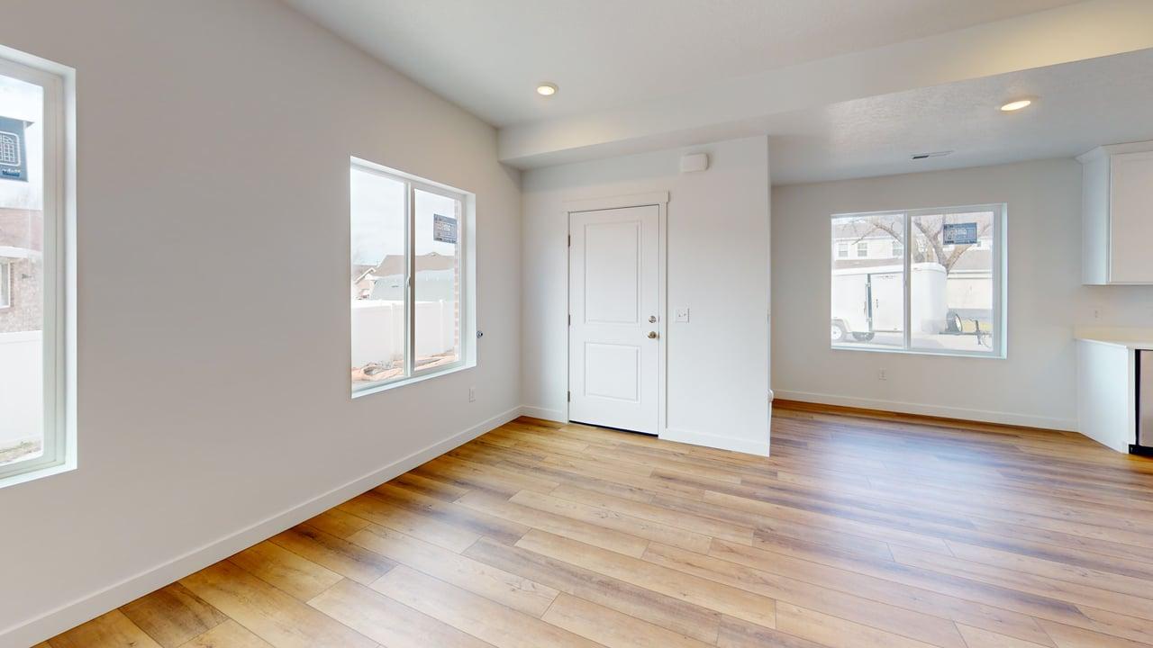 Open-concept living space with wood-finish flooring, recessed lighting, white walls, and multiple windows