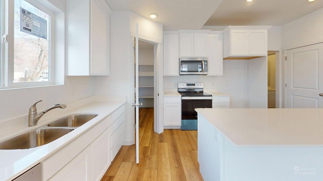Bright kitchen featuring white cabinetry, light countertops, wood-finish flooring, a stainless steel double sink, and a stainless steel microwave