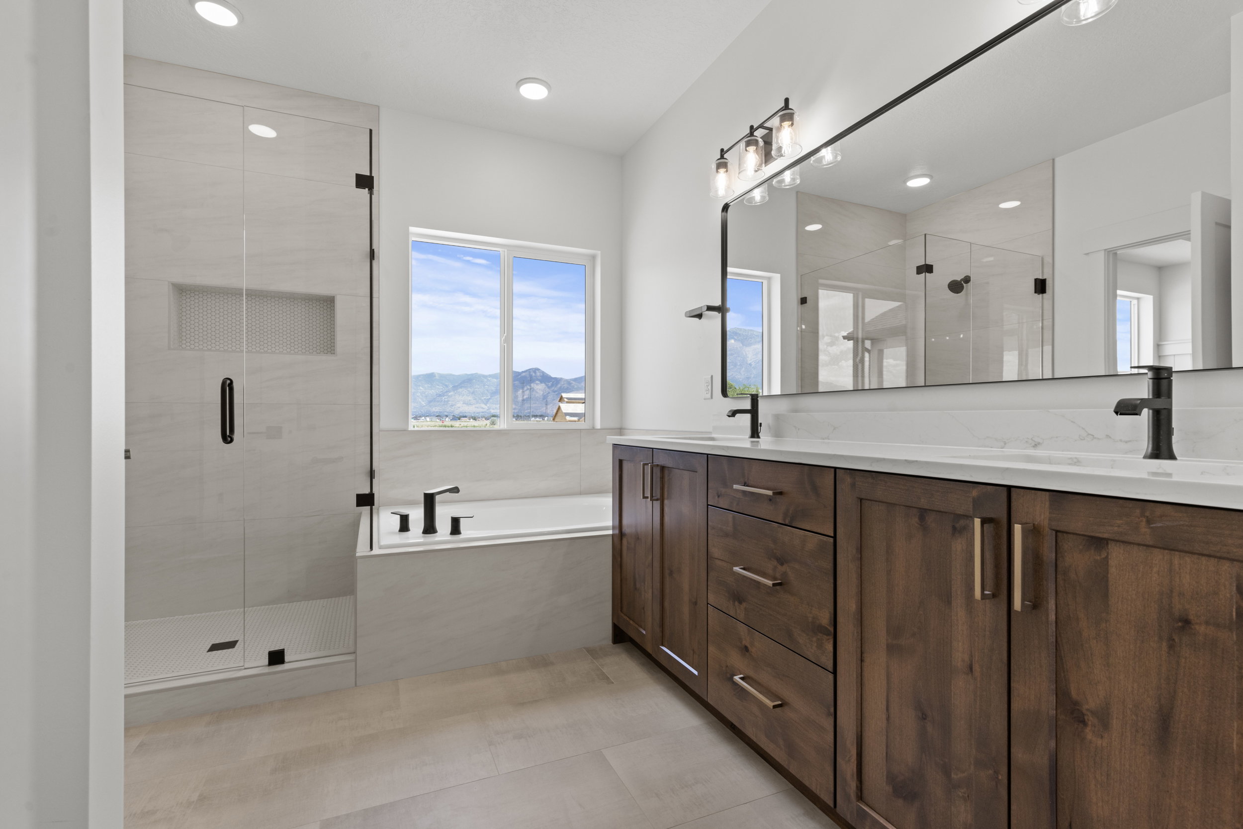 Bathroom featuring a double vanity with wood cabinetry, light-toned countertops, and matte black fixtures
