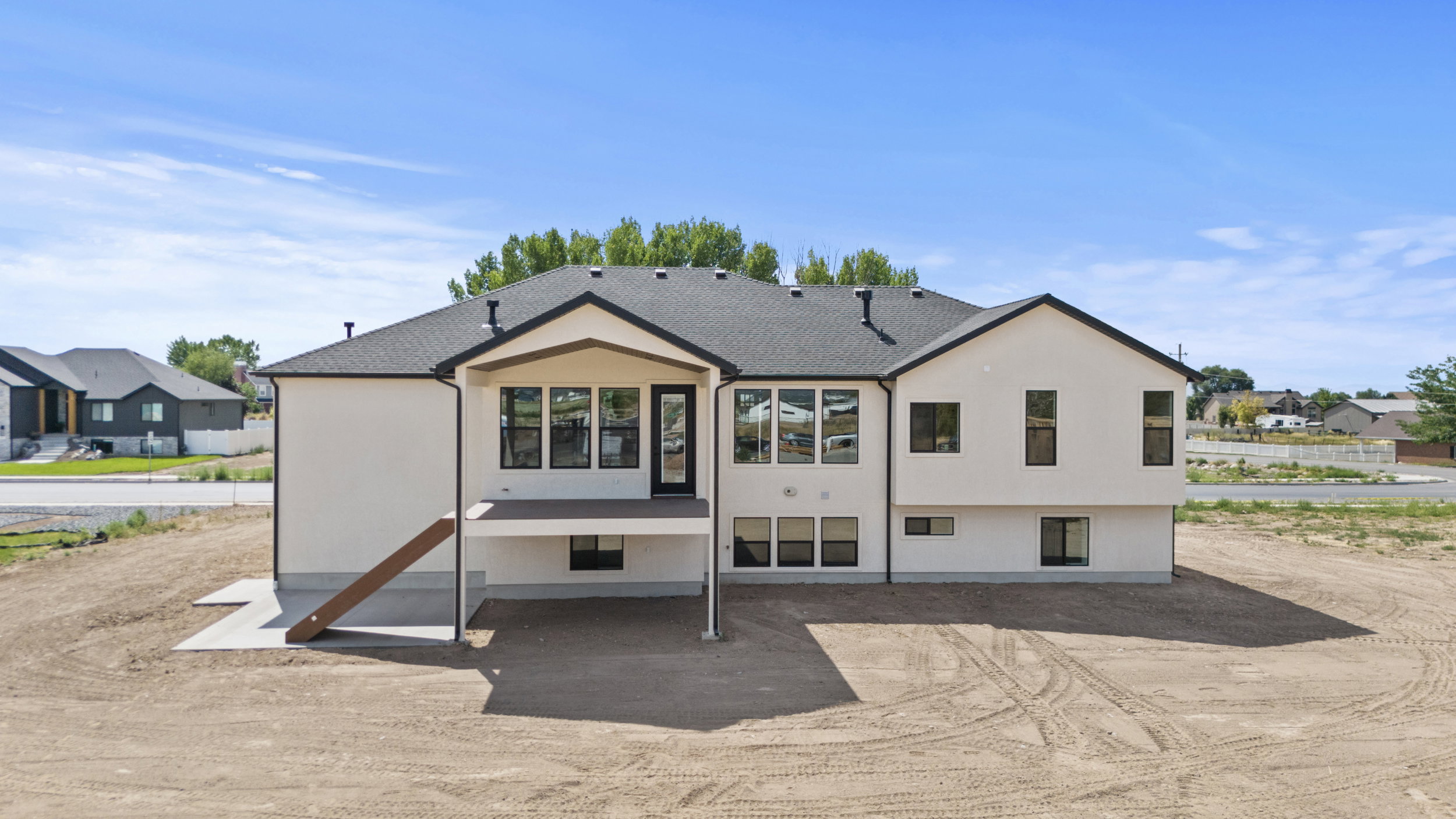 Modern stucco exterior with black-framed windows and a dark shingle roof