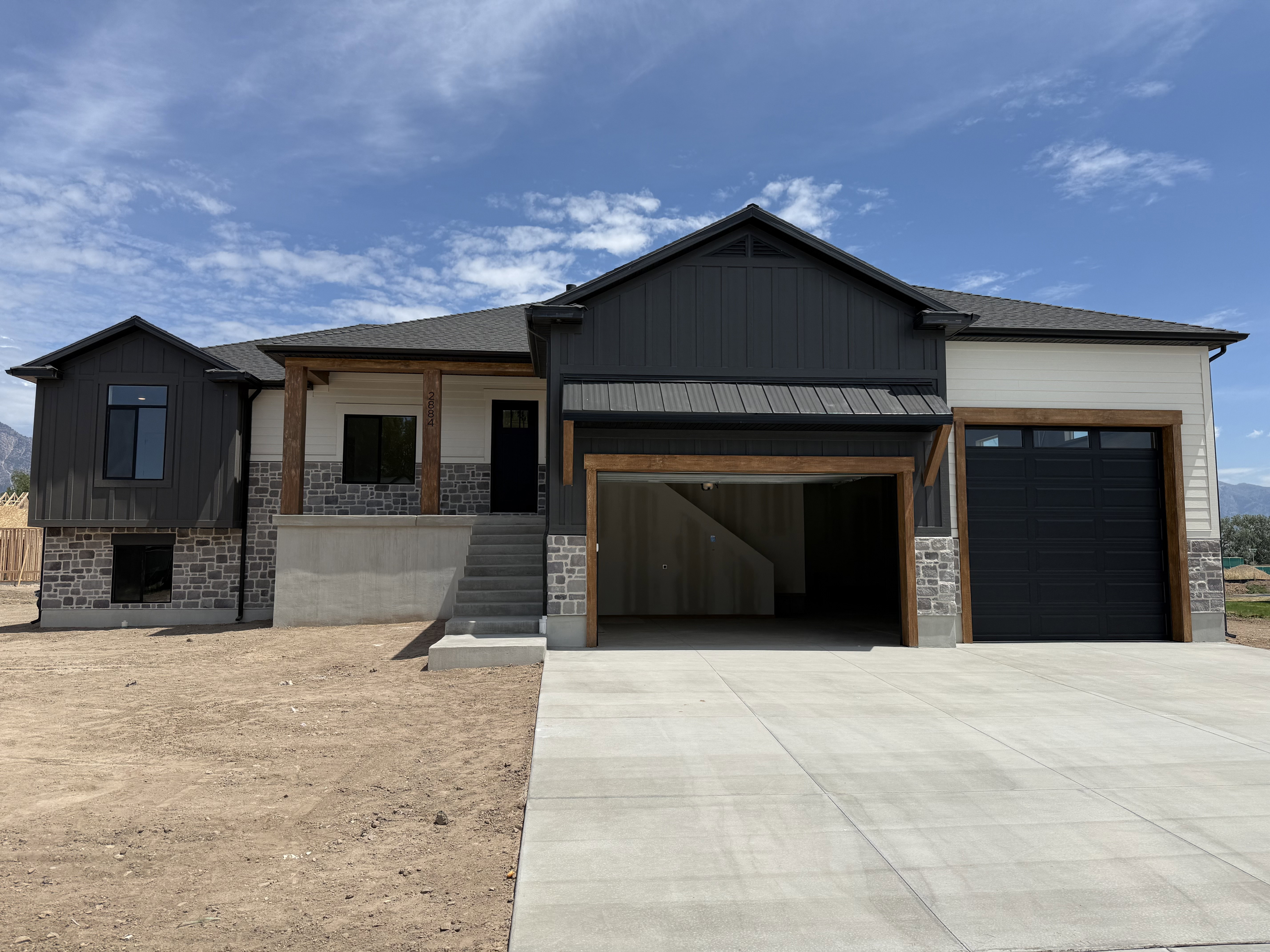 Contemporary-style residence featuring a dark gray and cream exterior with stone accents