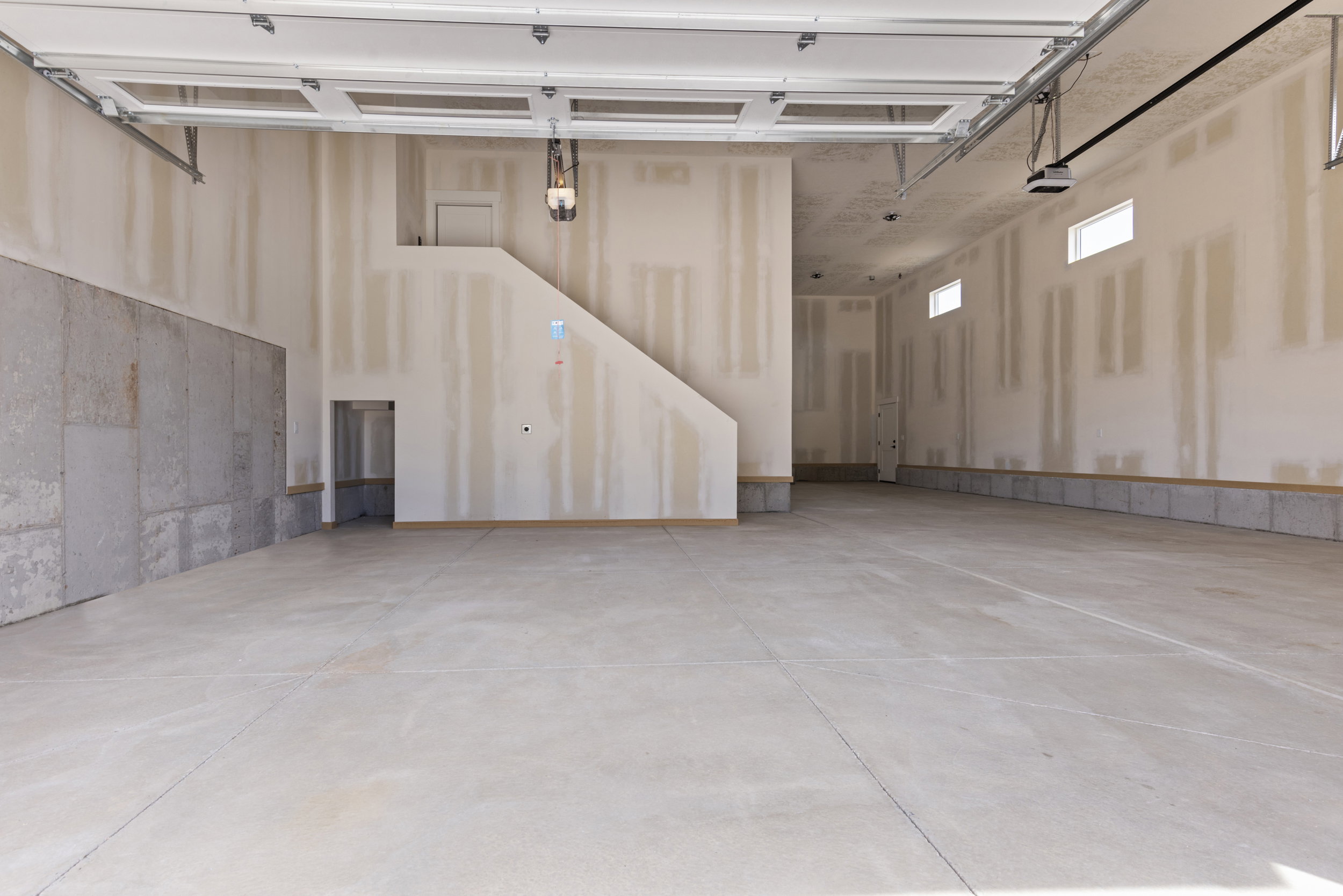 Spacious garage interior featuring a concrete floor, exposed foundation walls, and multiple small windows