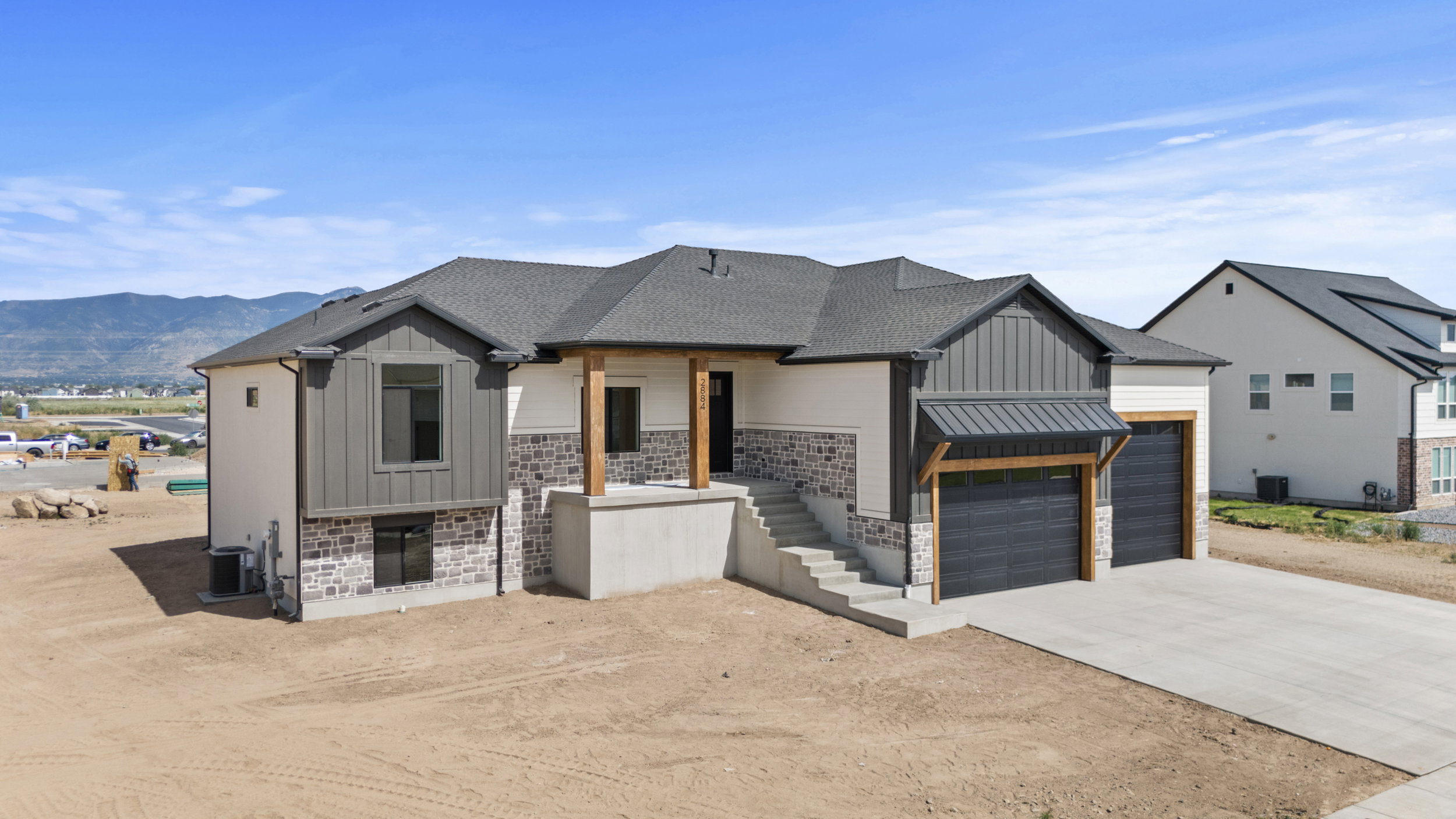 Contemporary residence featuring a two-car garage with black doors, a stone and siding exterior, and a prominent elevated entry