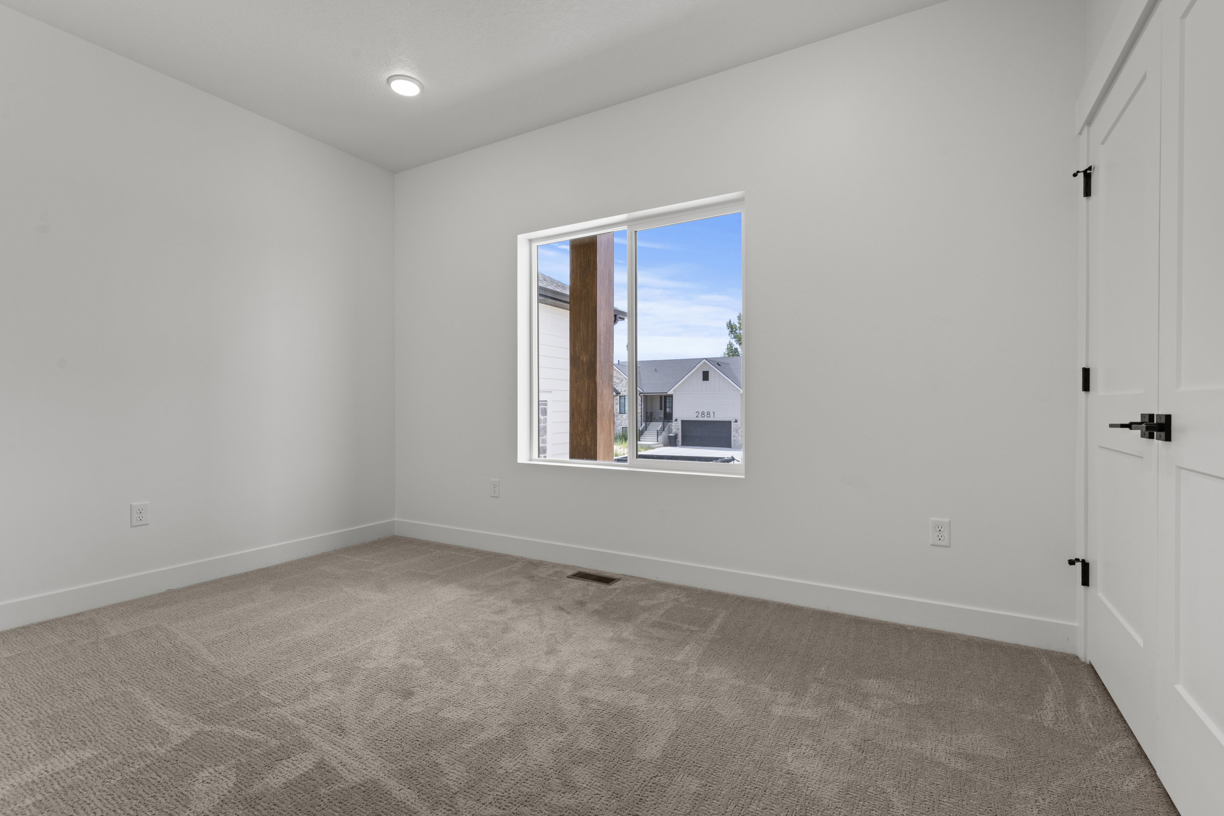 Neutral-toned wall-to-wall carpeting complements the white walls and trim