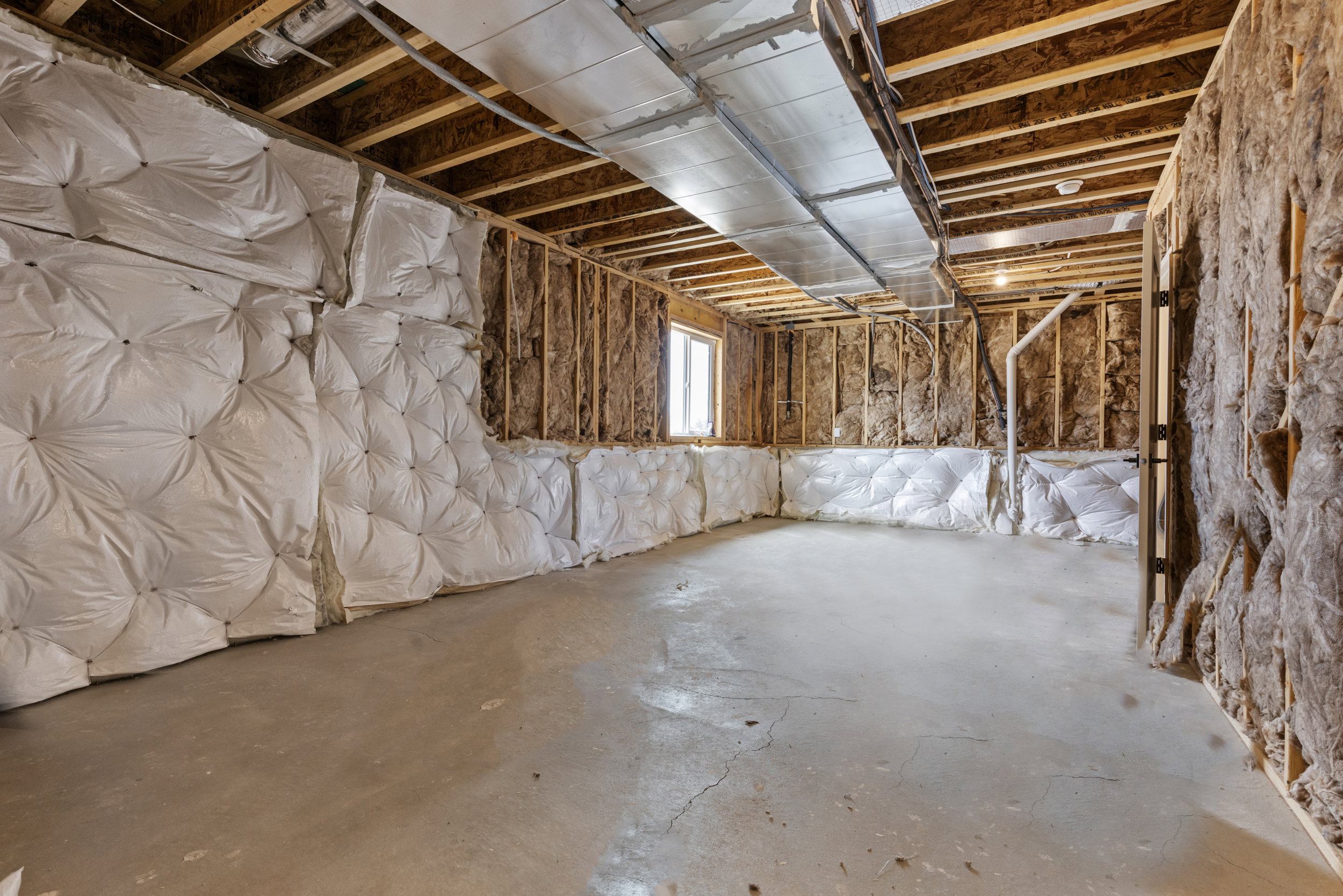 Unfinished basement featuring exposed wood framing, concrete flooring, and ceiling-mounted ductwork