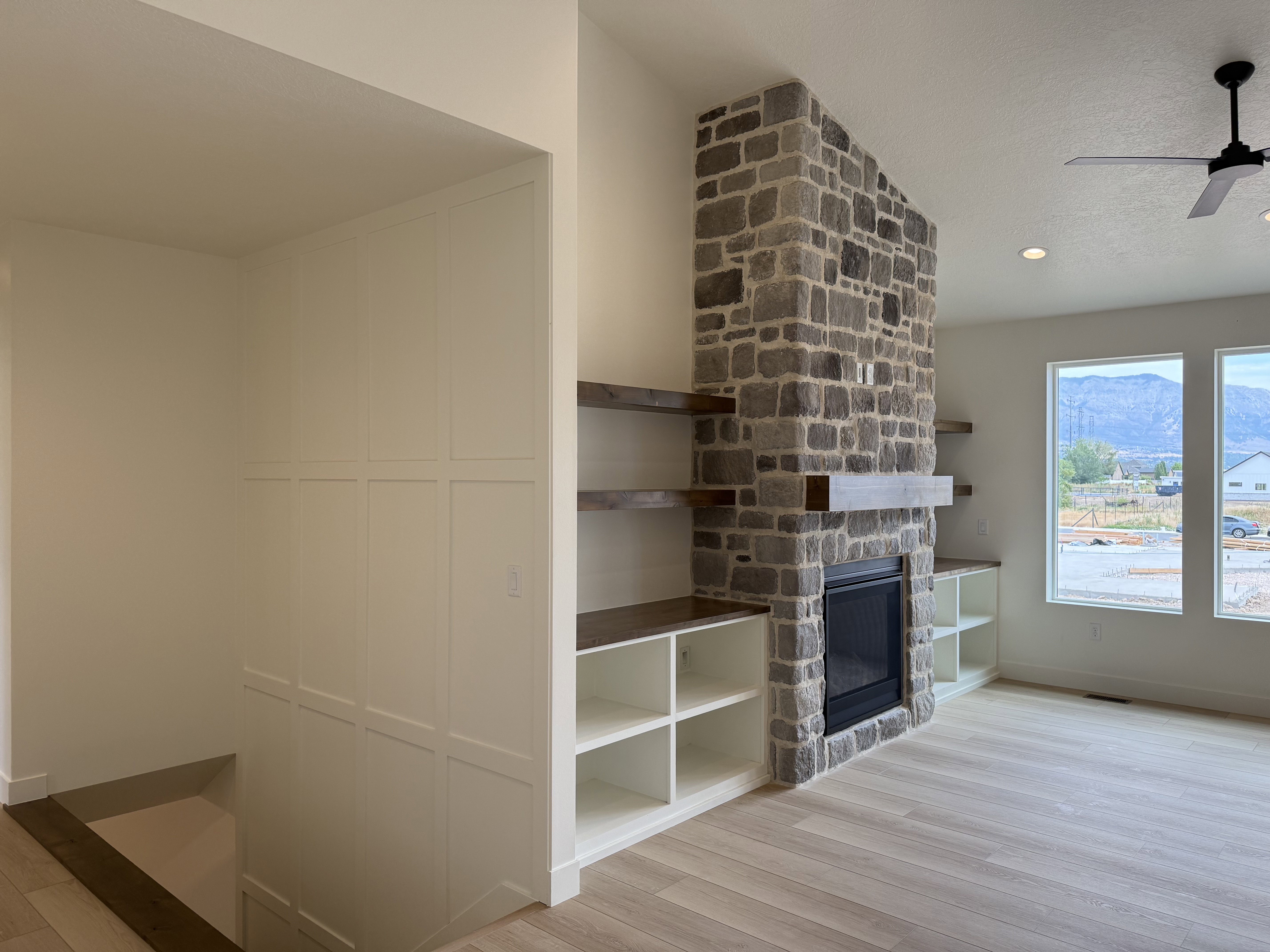 Stone-clad fireplace with a dark metal firebox and a wood mantel