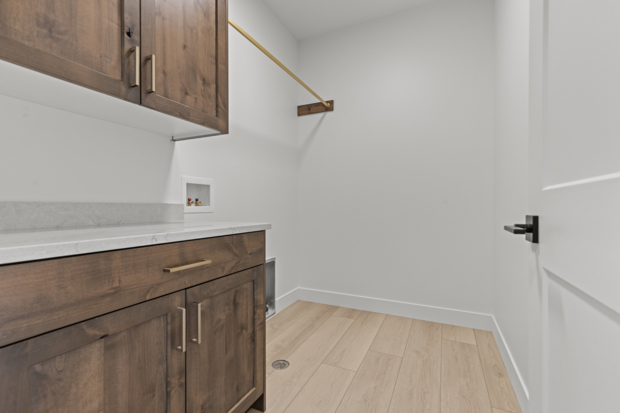 Laundry room featuring rich wood cabinetry, light-toned countertops, and light wood-finish flooring