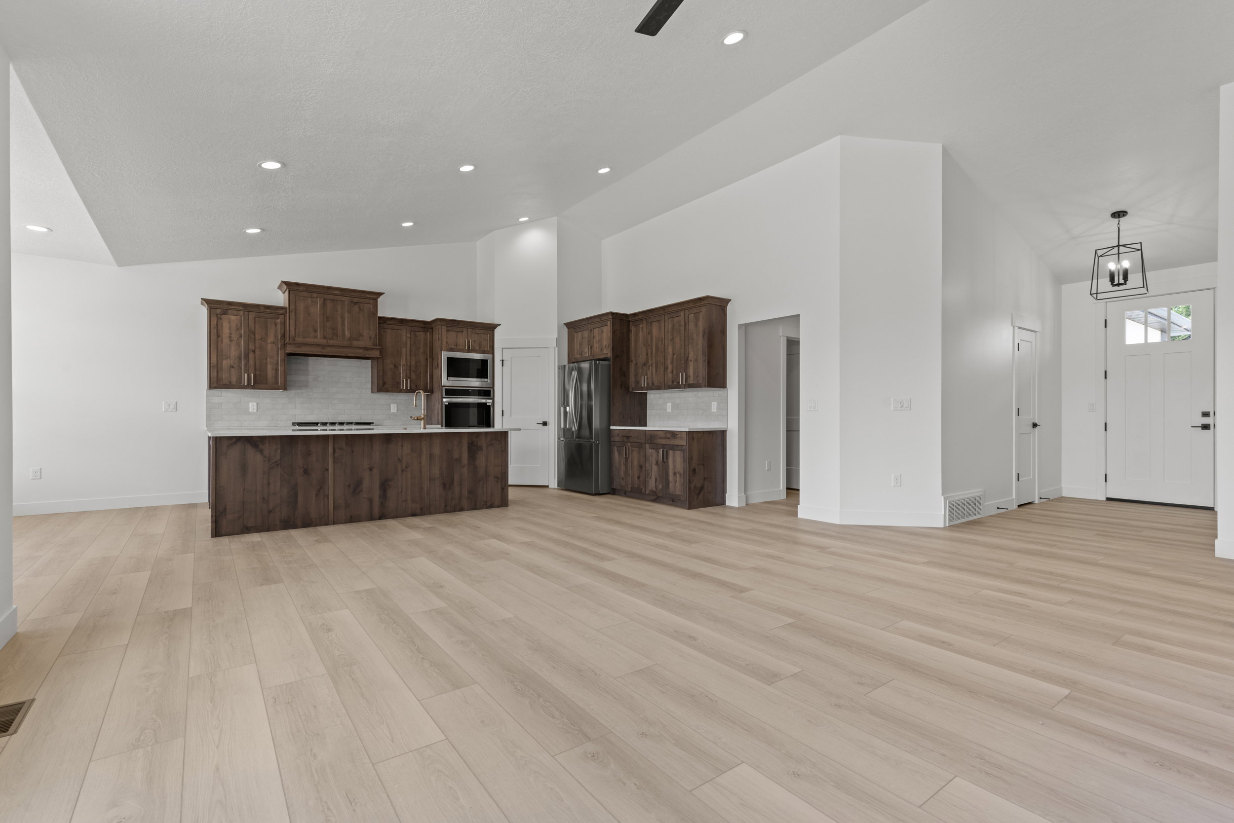 Bright, open-concept living space featuring light wood-finish flooring and vaulted ceilings