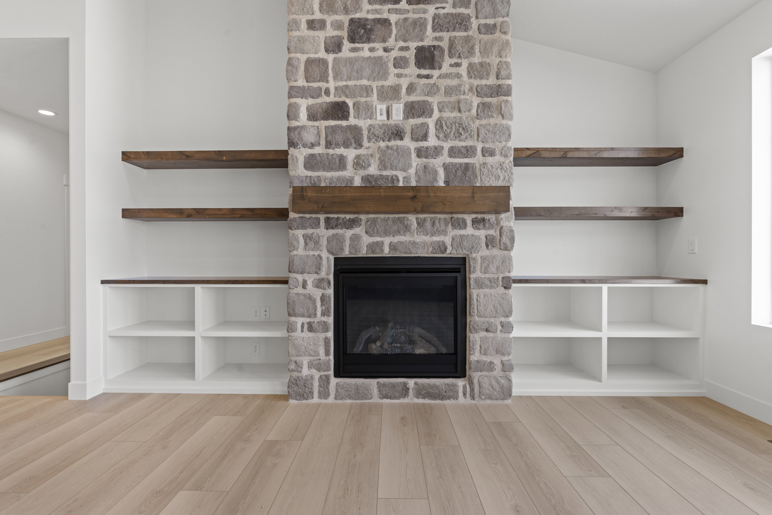 Stone-clad fireplace featuring a wood mantel and black firebox