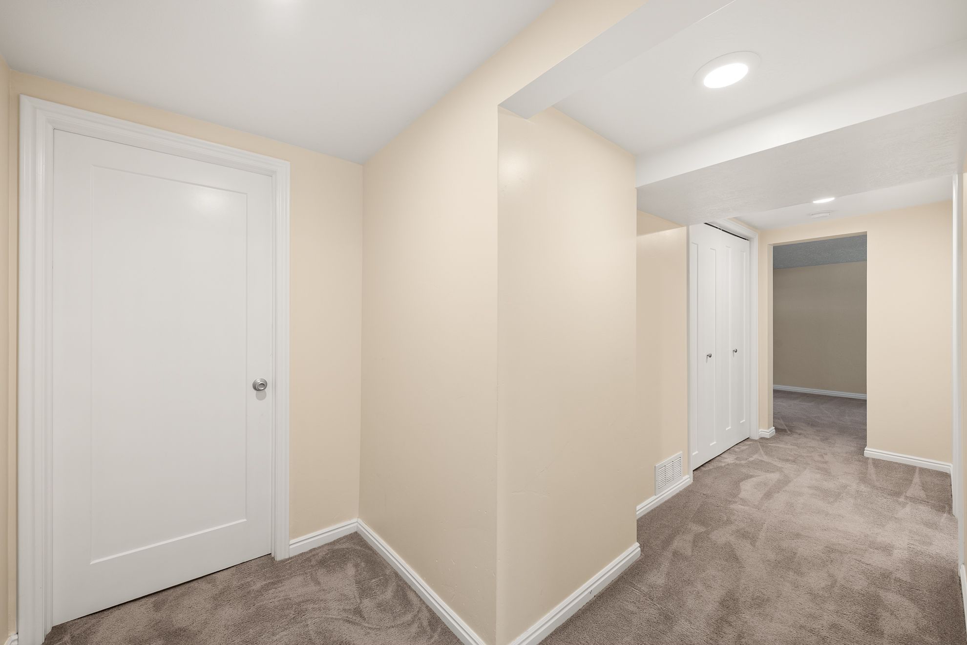 Interior hallway with beige walls, gray carpet, and white trim