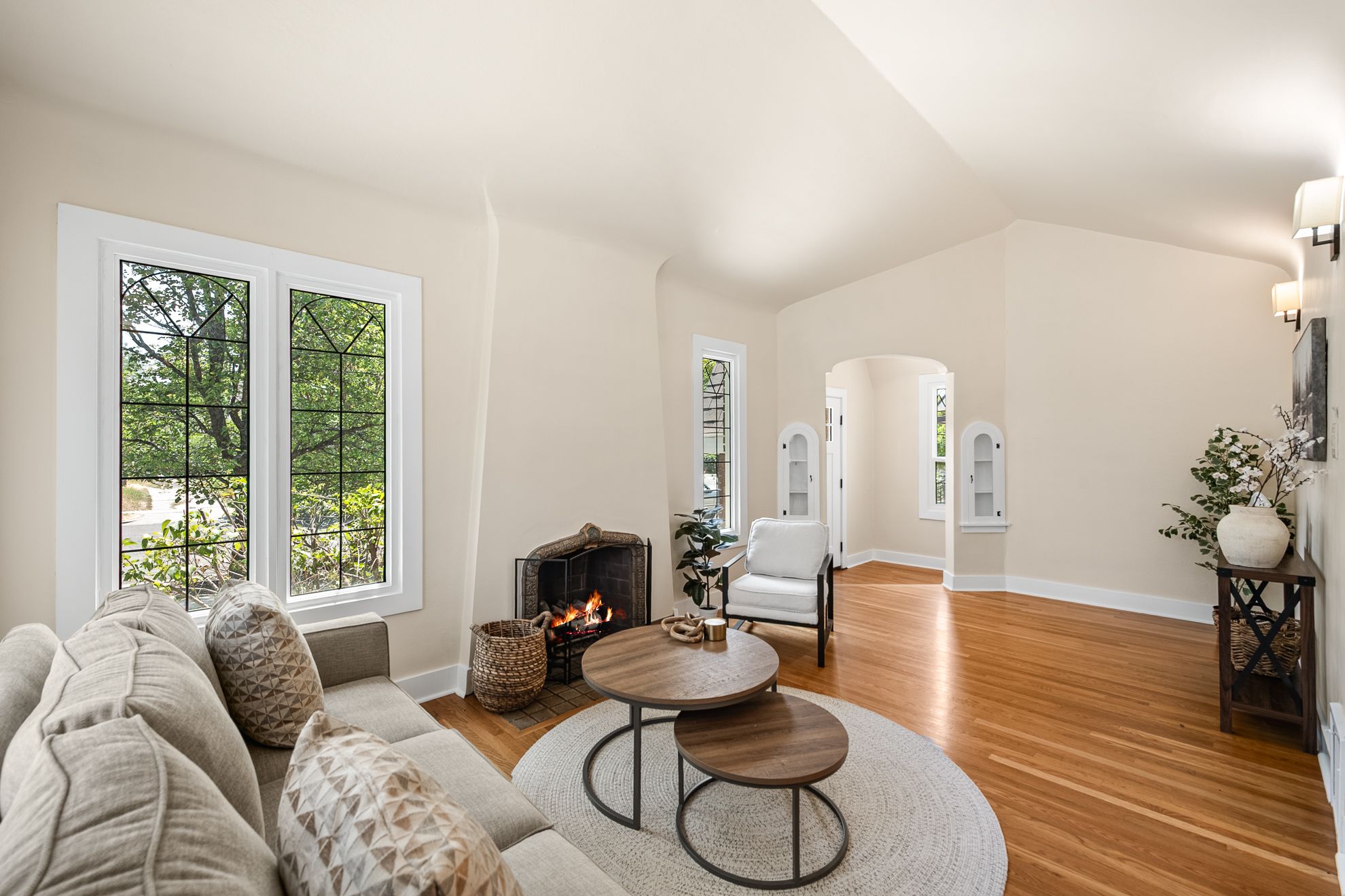 Spacious living area featuring hardwood flooring, a vaulted ceiling, and ample natural light from leaded glass windows