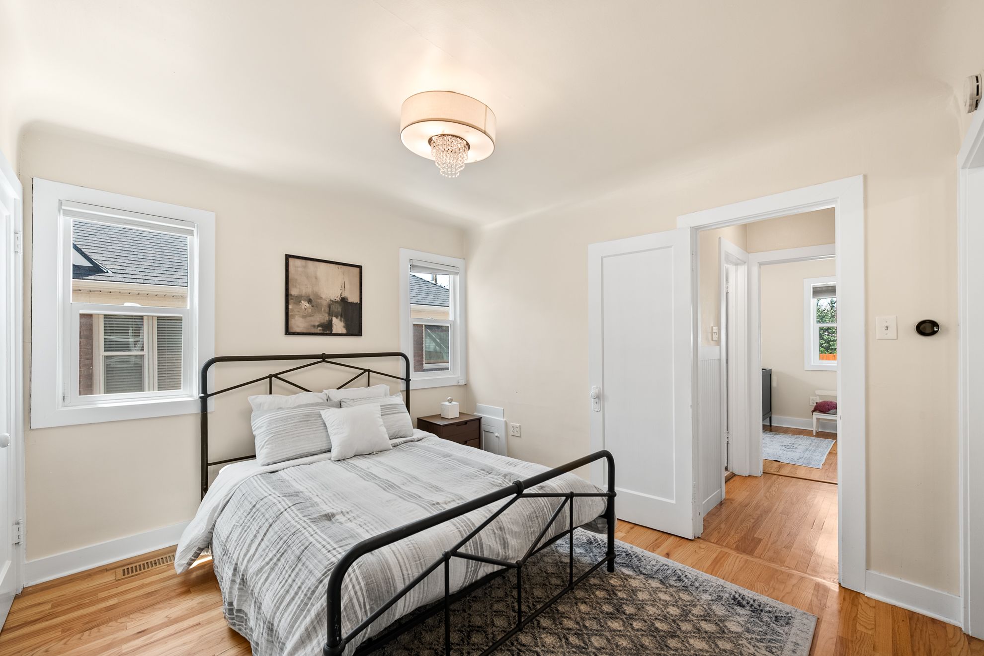 Hardwood flooring throughout, featuring multiple windows, a flush mount ceiling fixture, and white trim molding