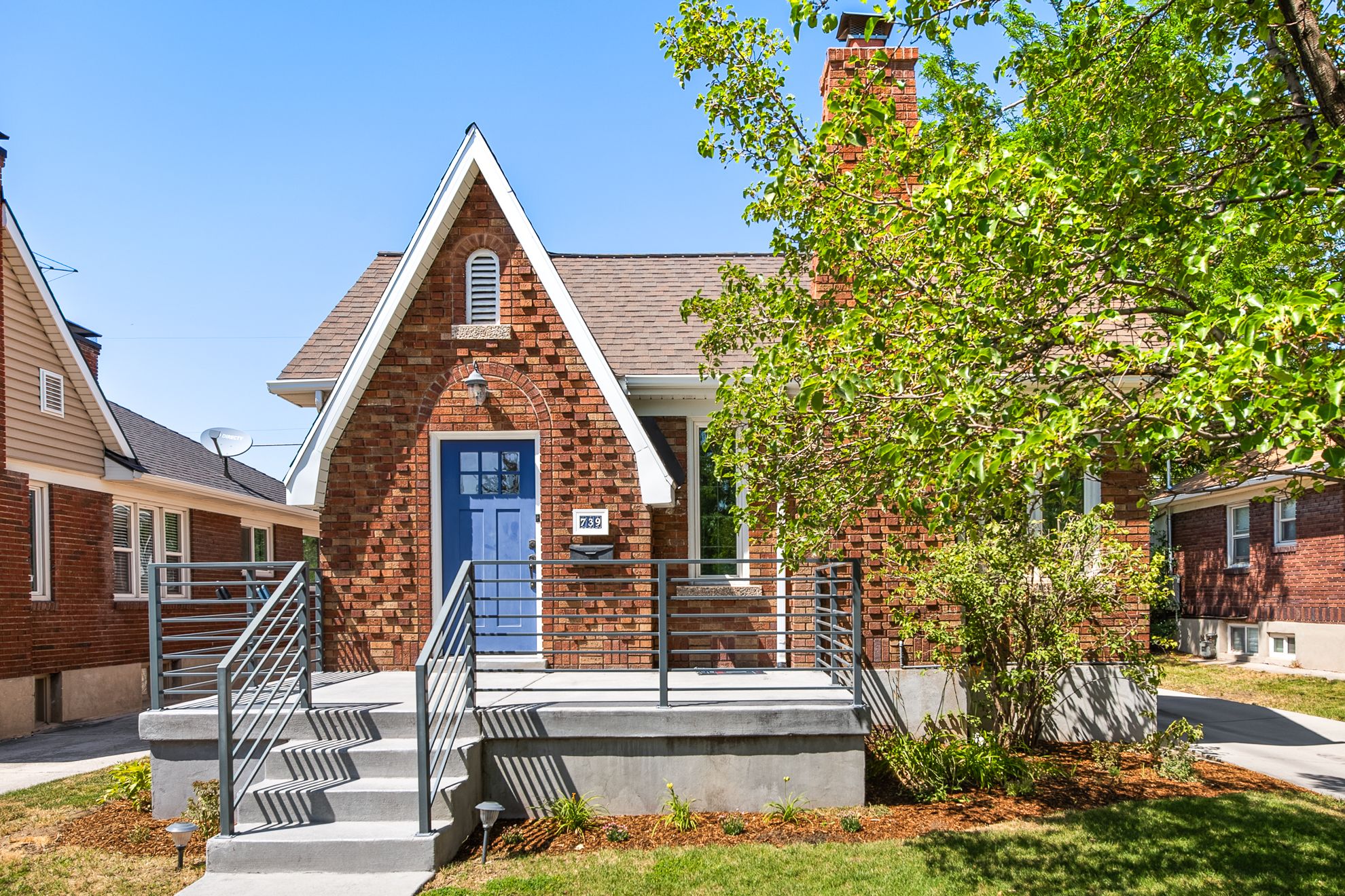 Brick exterior featuring a steeply pitched gable roofline, arched entry, and a striking blue front door