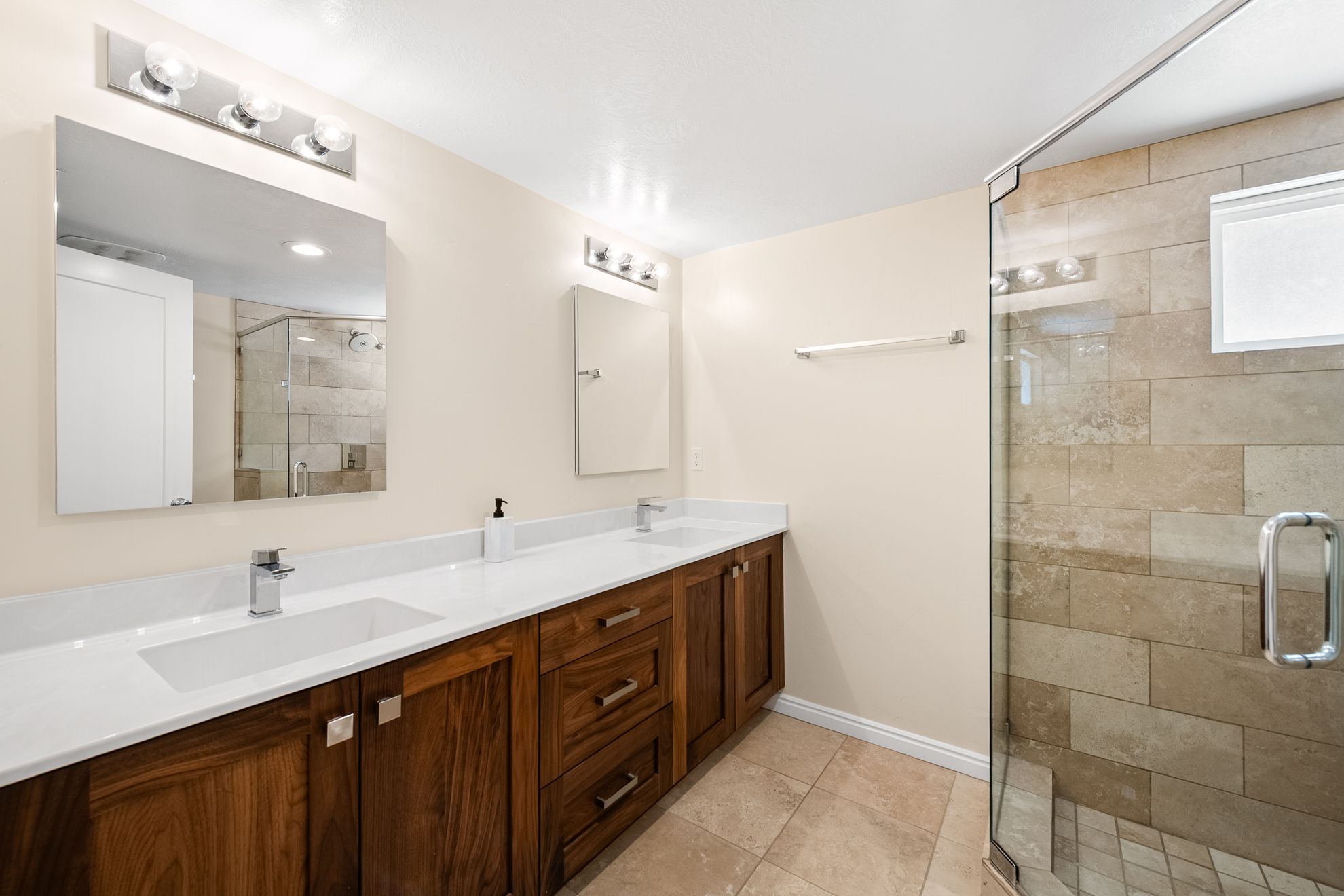 Dual vanity with white countertops and undermount sinks, featuring wood-finish cabinetry