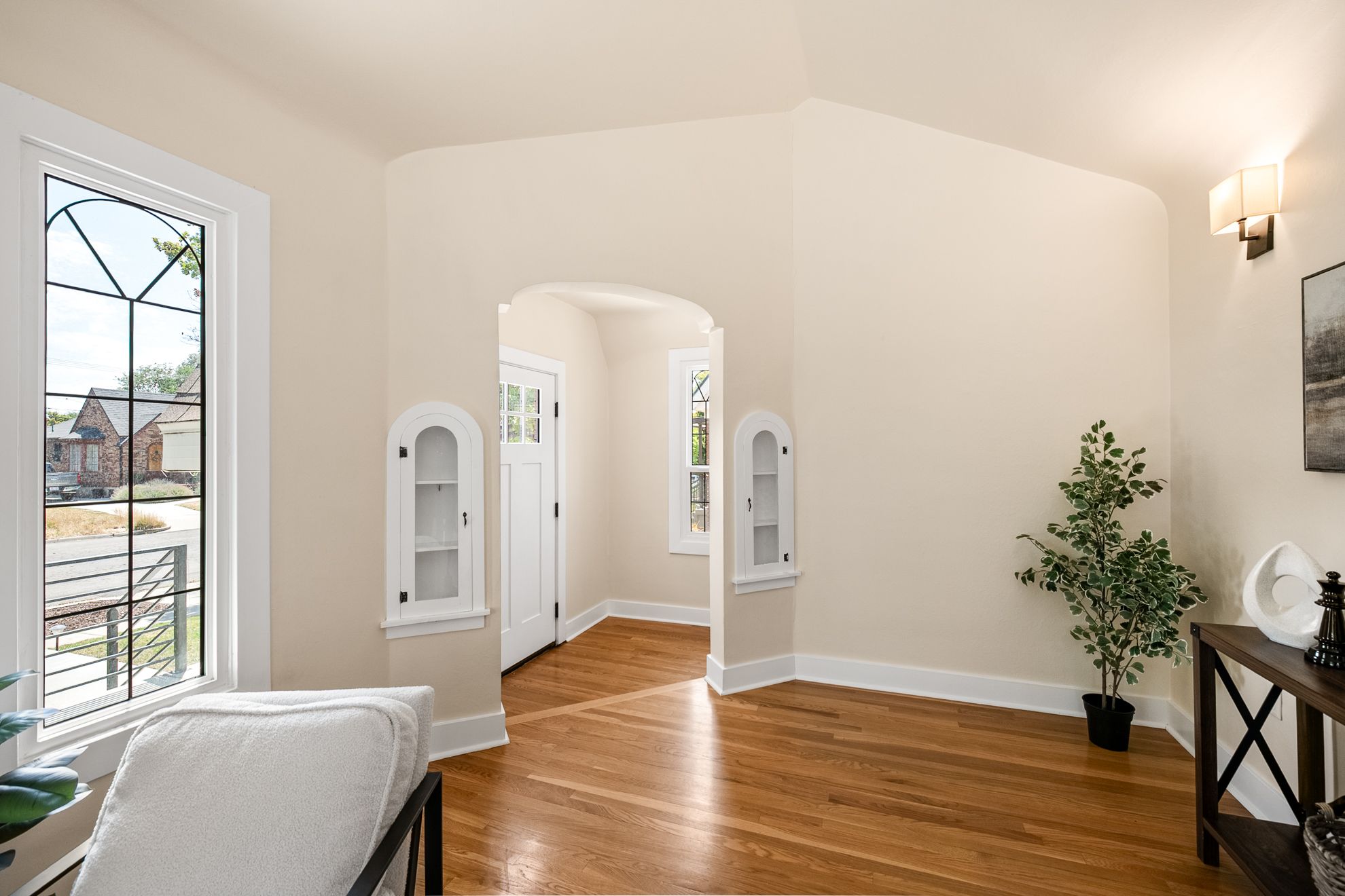 Entryway featuring a white paneled door with glass inserts, hardwood flooring, and an arched doorway