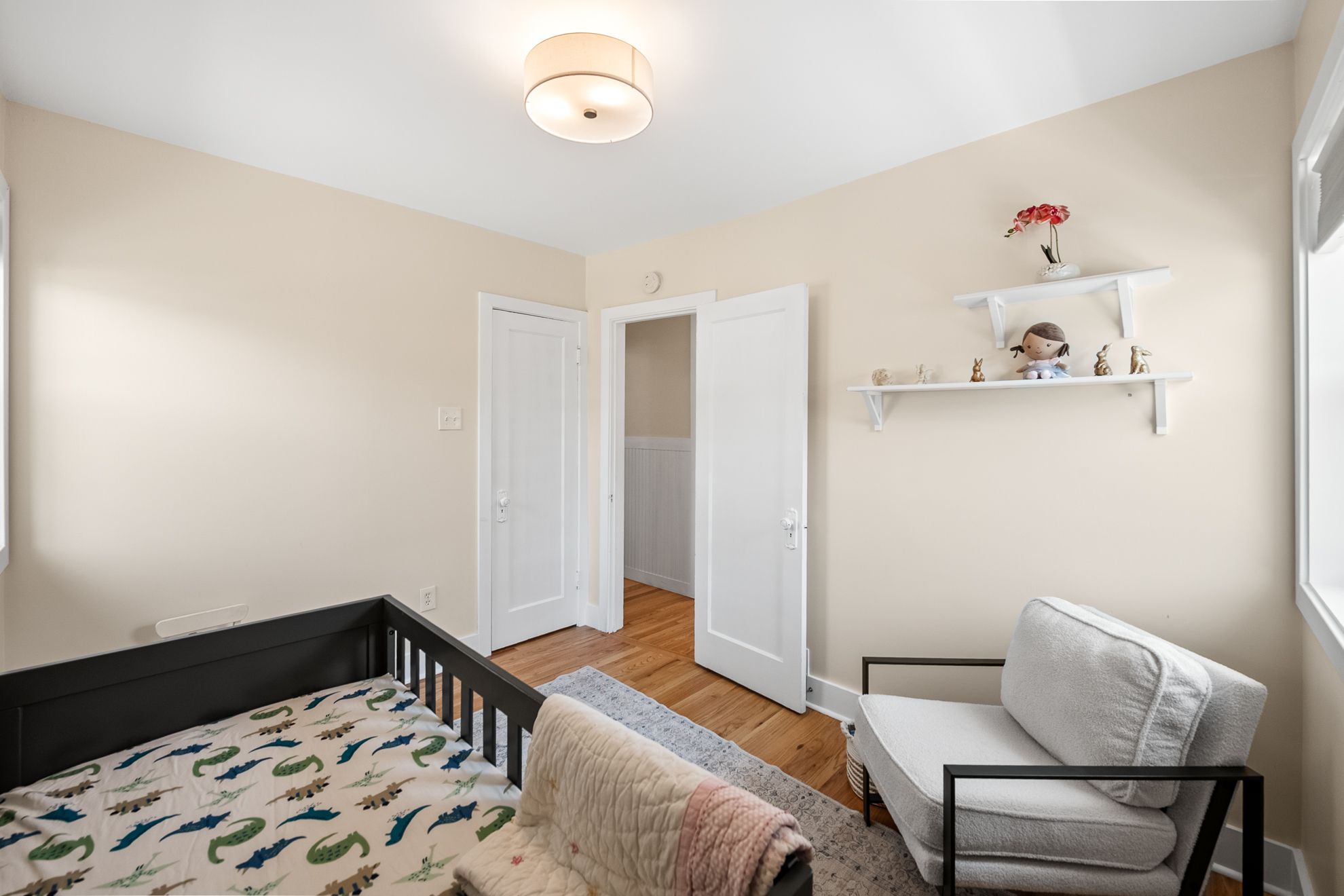 Light-filled room featuring wood-finish flooring, neutral wall tones, white trim, and a flush mount ceiling light