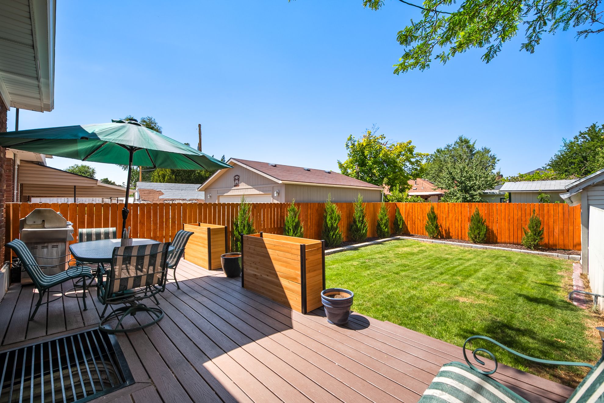 Backyard featuring a composite deck, manicured lawn, and a newly stained wood privacy fence