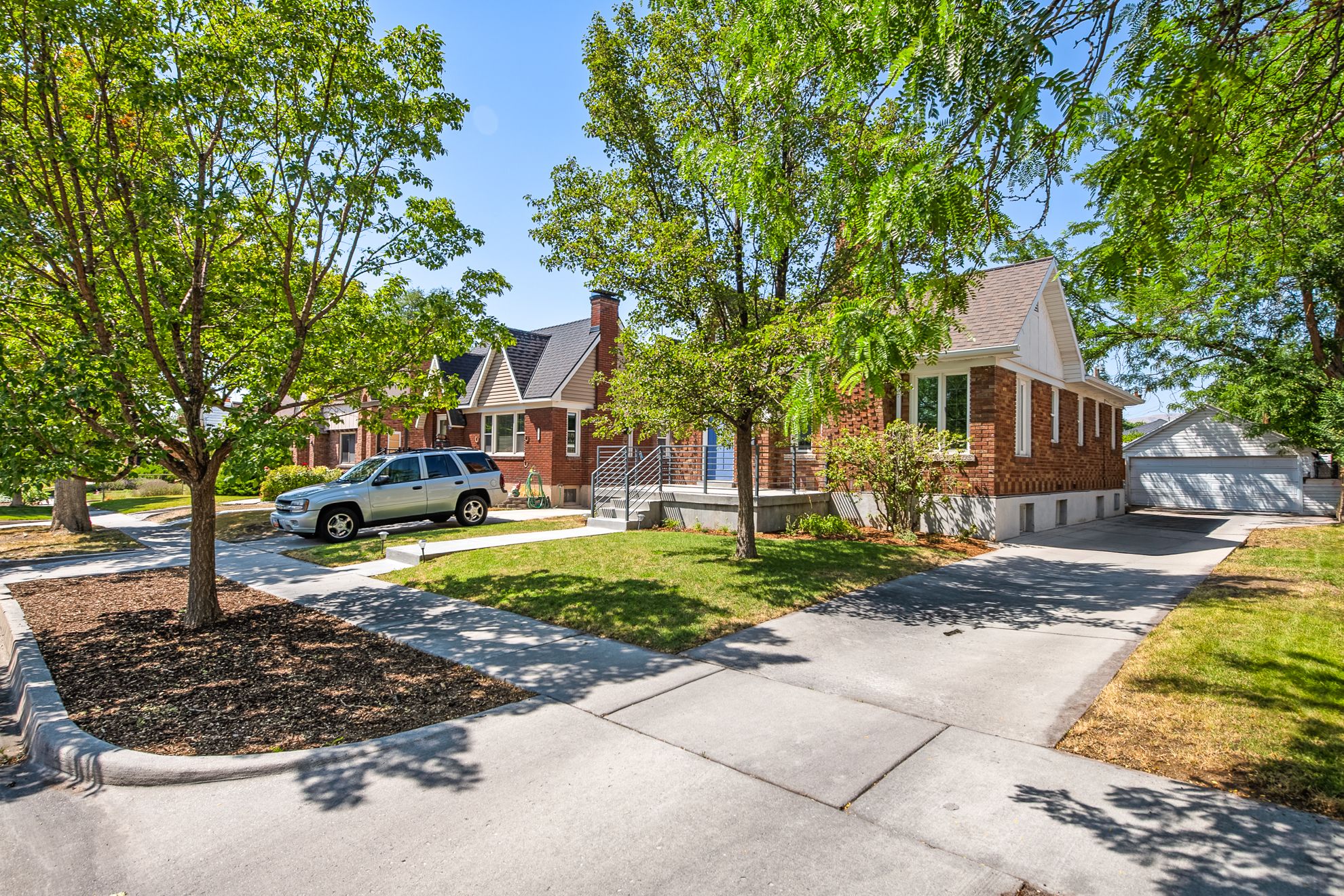 Traditional brick residence featuring a prominent gabled roofline, multiple windows, and a concrete driveway leading to a detached garage