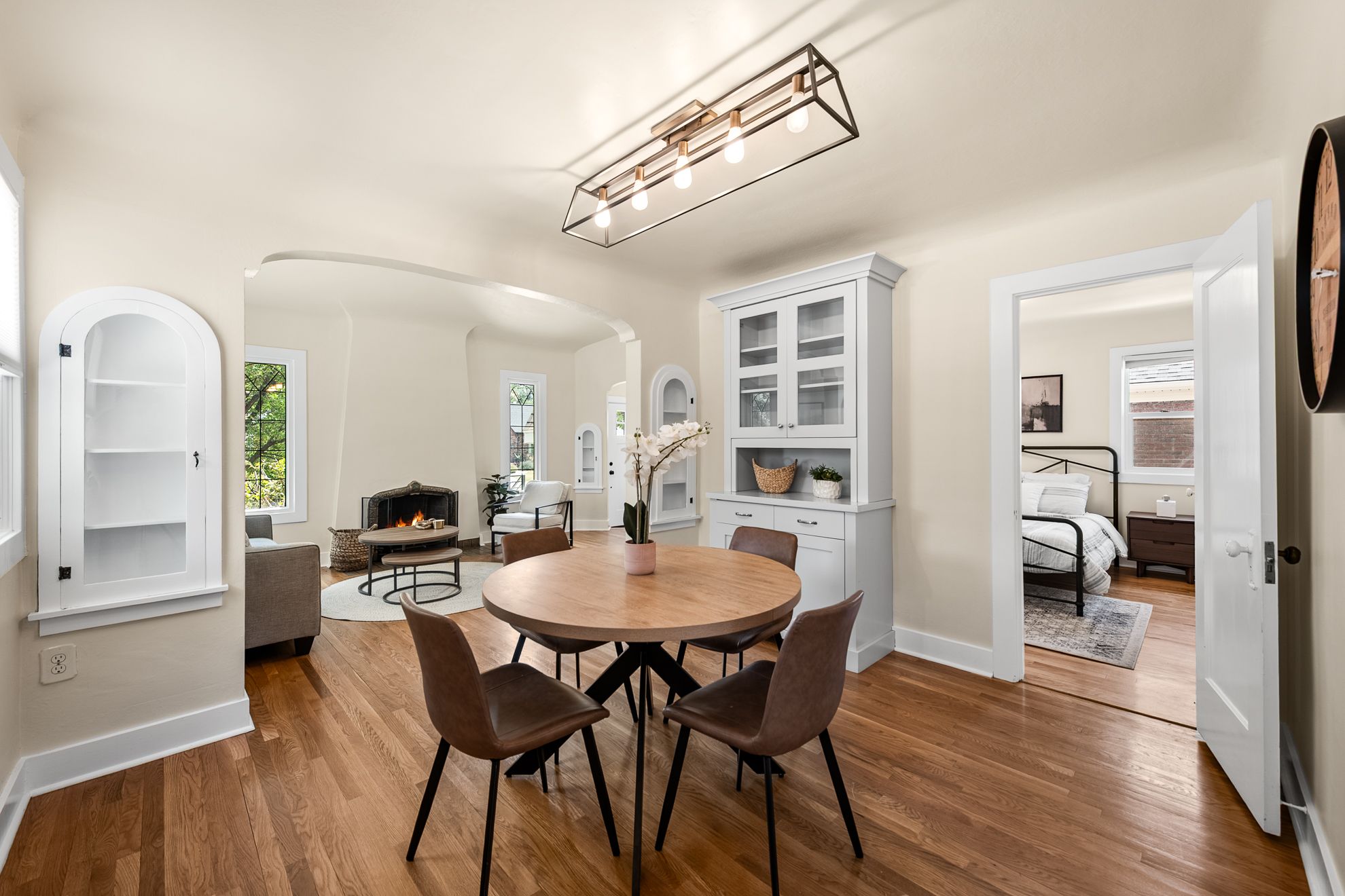 Dining area featuring wood-finish flooring, a contemporary linear chandelier, and an integrated built-in china cabinet with glass-front doors