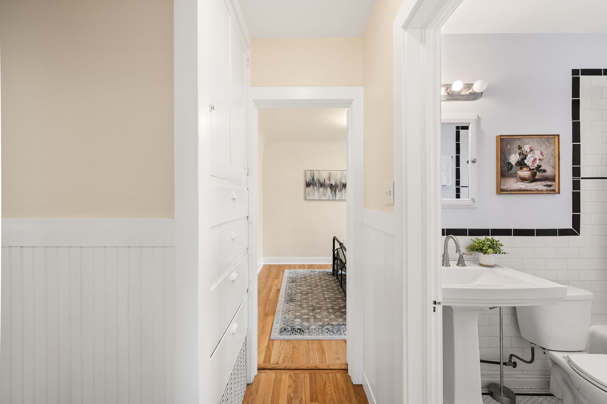 Hallway featuring wood-finish flooring, white beadboard wainscoting, and built-in storage cabinetry