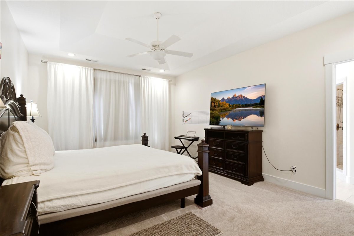 Bedroom featuring a tray ceiling with recessed lighting and a ceiling fan