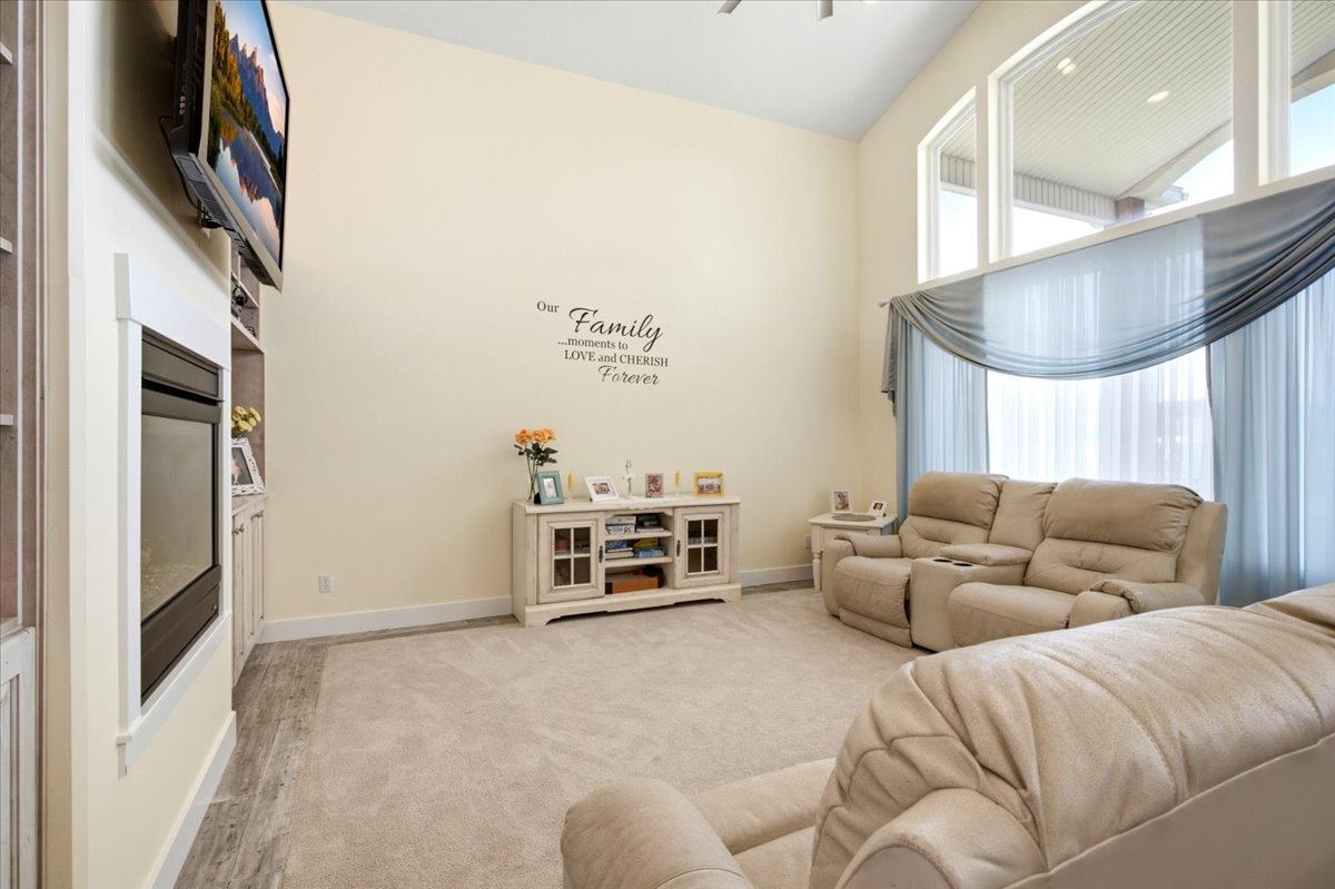 Living space featuring vaulted ceilings, a built-in fireplace with shelving, and large windows