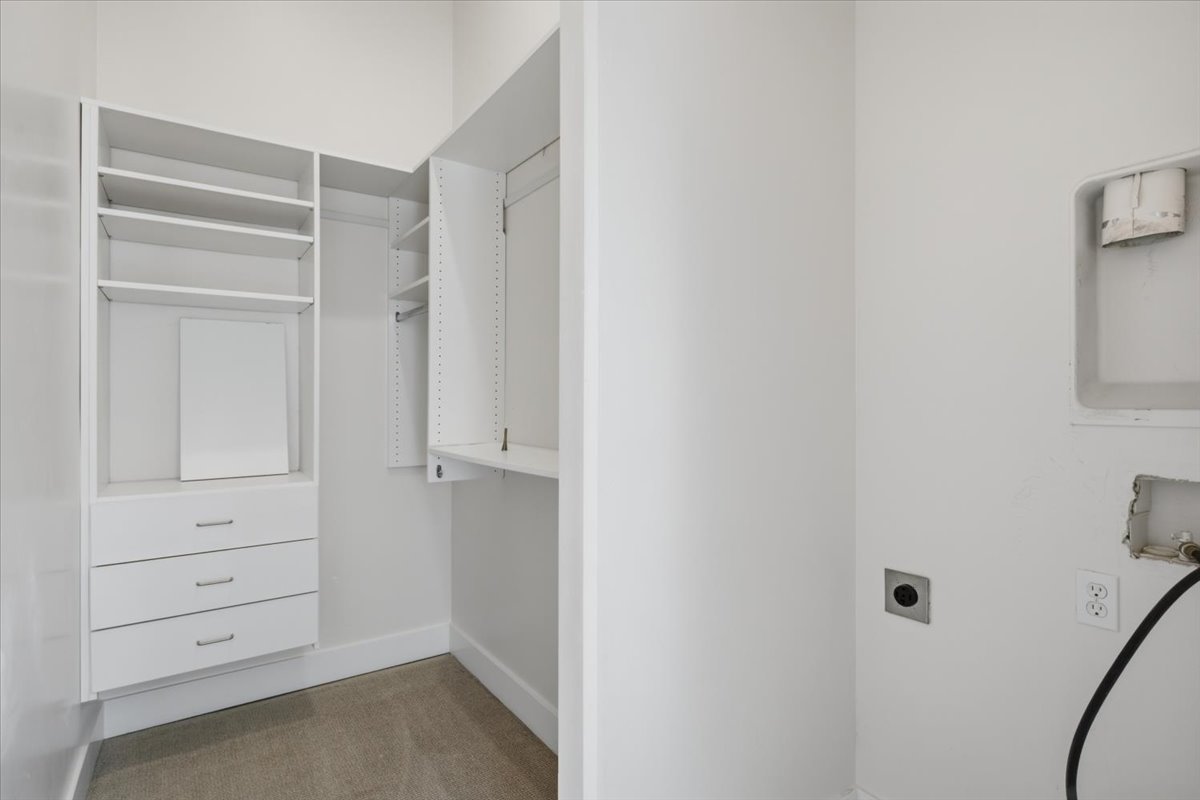 Laundry space featuring a walk-in closet with built-in shelving, drawers, and hanging rods