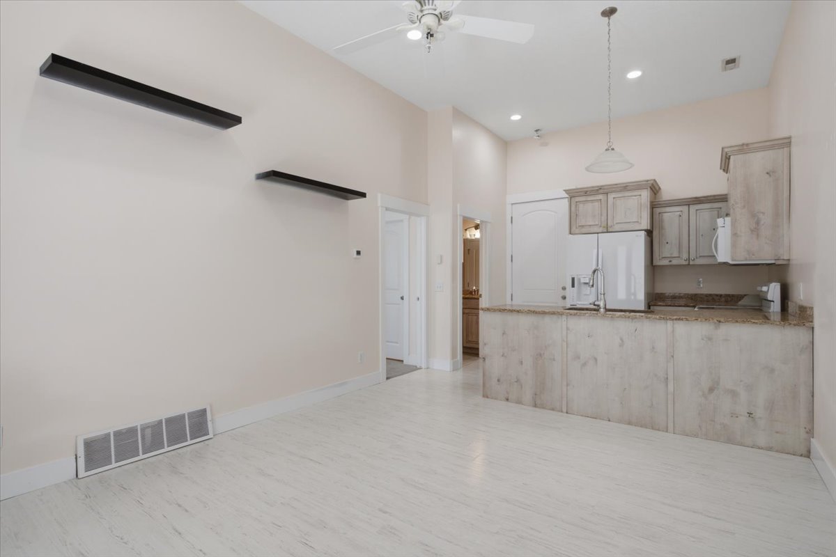 Open-concept room featuring wood-finish flooring, high ceilings, and recessed lighting