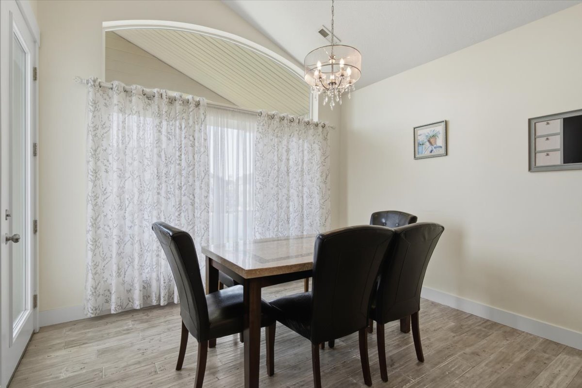 Vaulted ceiling room featuring light-colored walls and wood-finish flooring